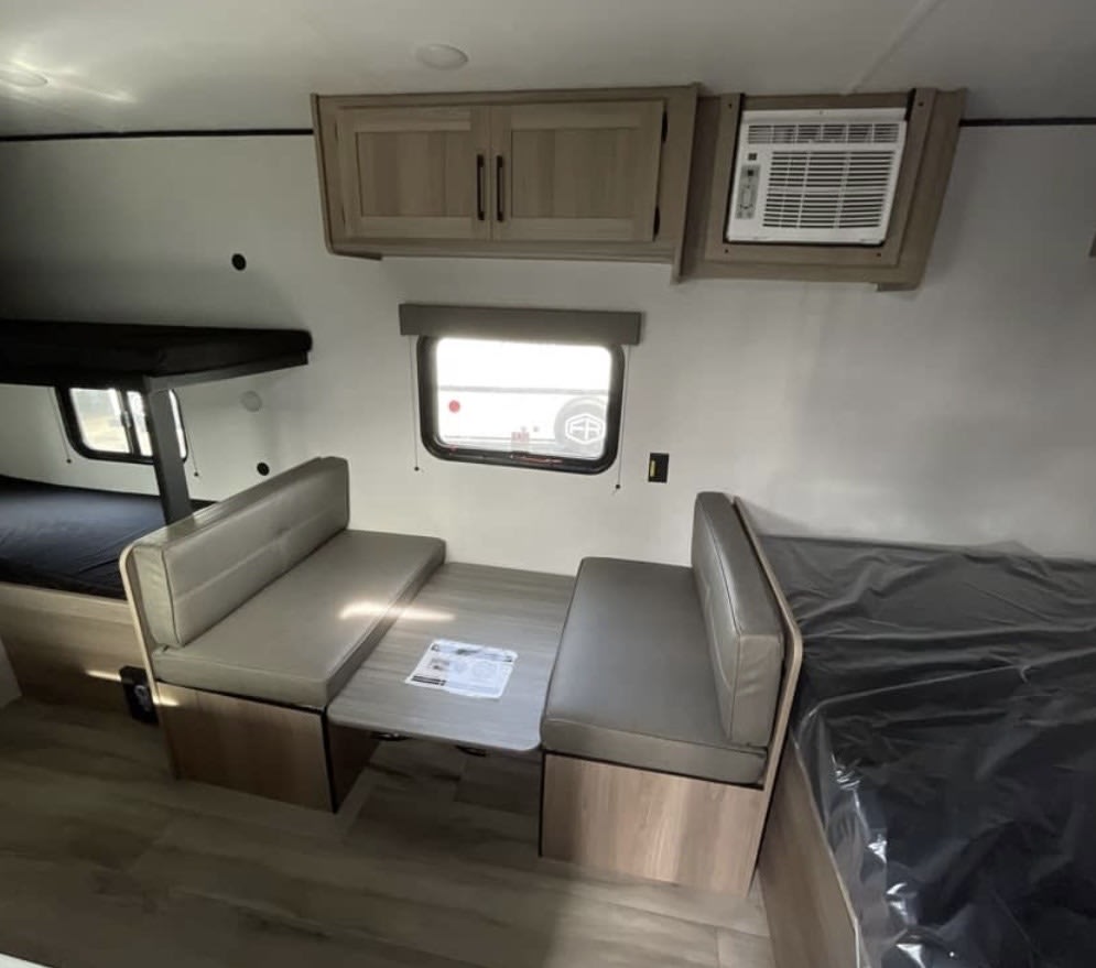 RV rental interior: dinette with table, bunk beds, and wall-mounted AC unit visible. Compact, functional design.. Keystone RV Coleman 2025
