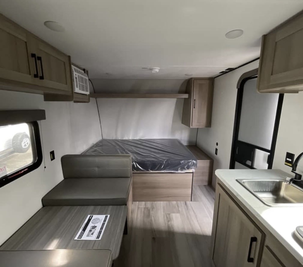 Cozy RV rental interior with a bed, dinette, kitchen, and overhead storage, perfect for travel adventures.. Keystone RV Coleman 2025
