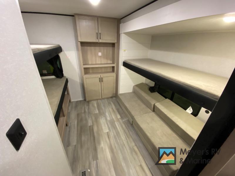 This RV rental interior features comfortable bunk beds, built-in storage, and versatile cushioned seating, ideal for your next adventure.. Heartland Prowler 3202DSB 2026