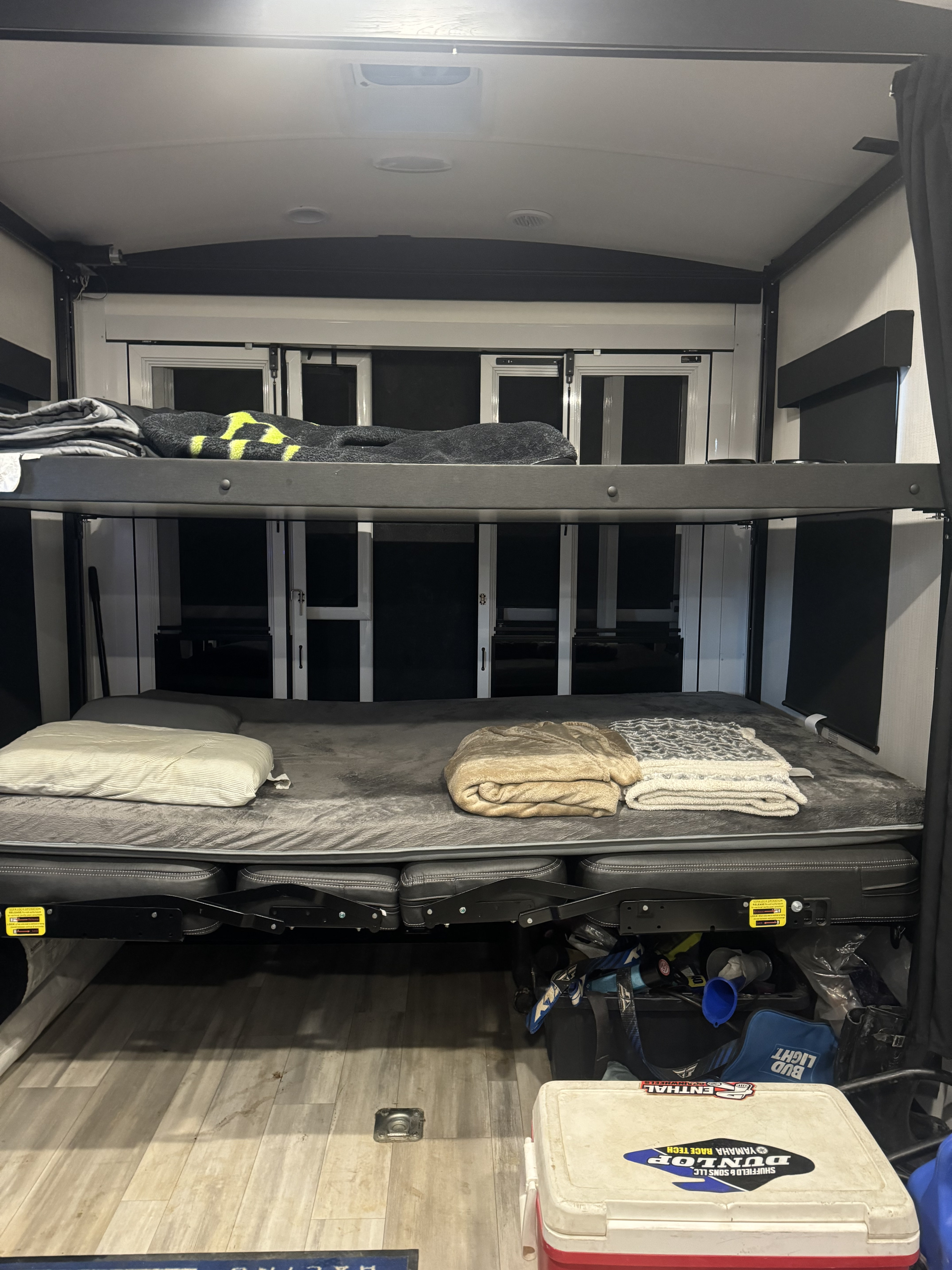 RV rental interior featuring comfortable bunk beds, with bedding, a pillow, and blankets. A cooler and gear are stored below.. Cruiser Rv Corp Stryker 2024