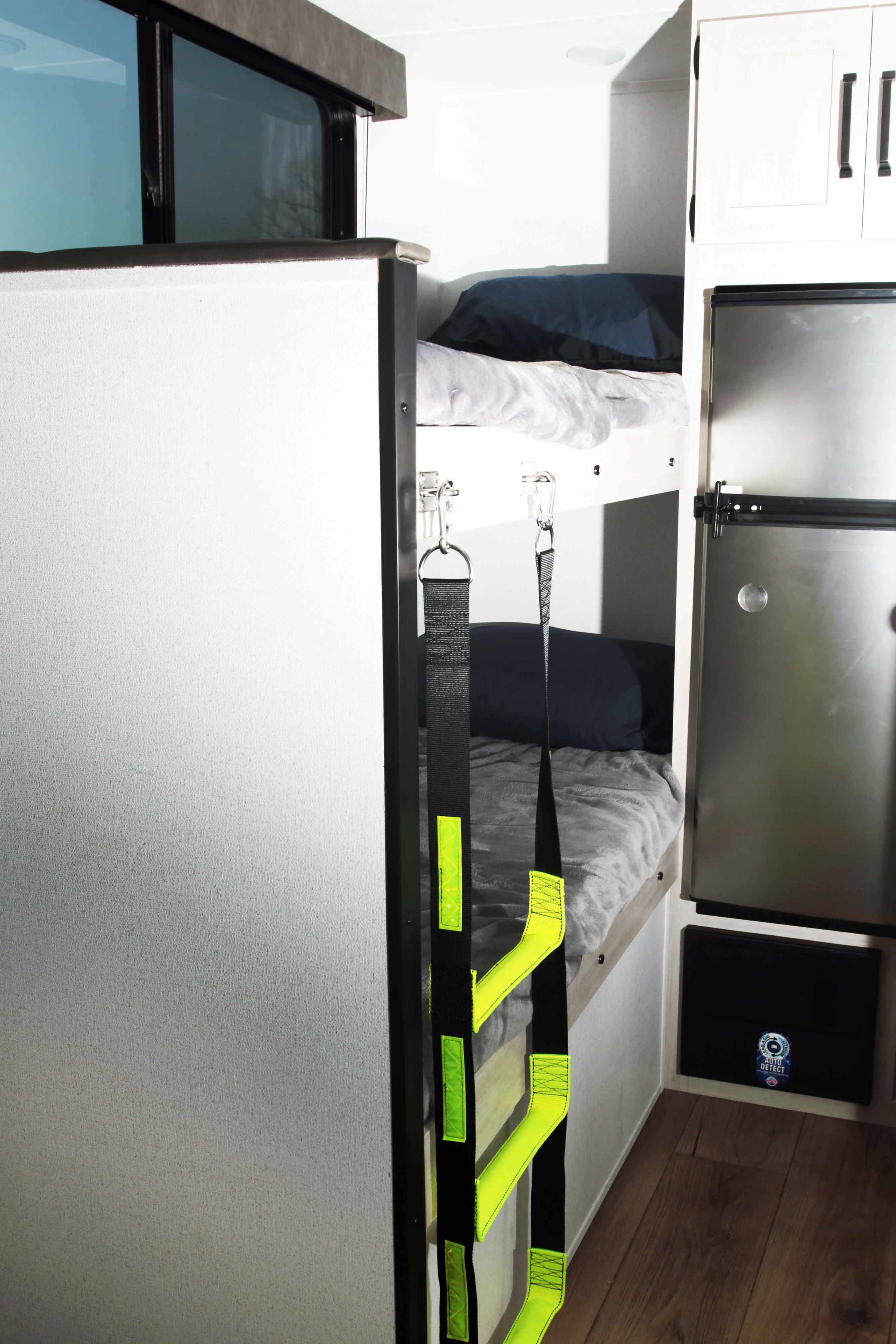 An RV rental interior featuring cozy bunk beds with a bright ladder, a refrigerator, and storage cabinets for comfortable family travel.. Palomino Puma Camping Edition 122BHCE 2026