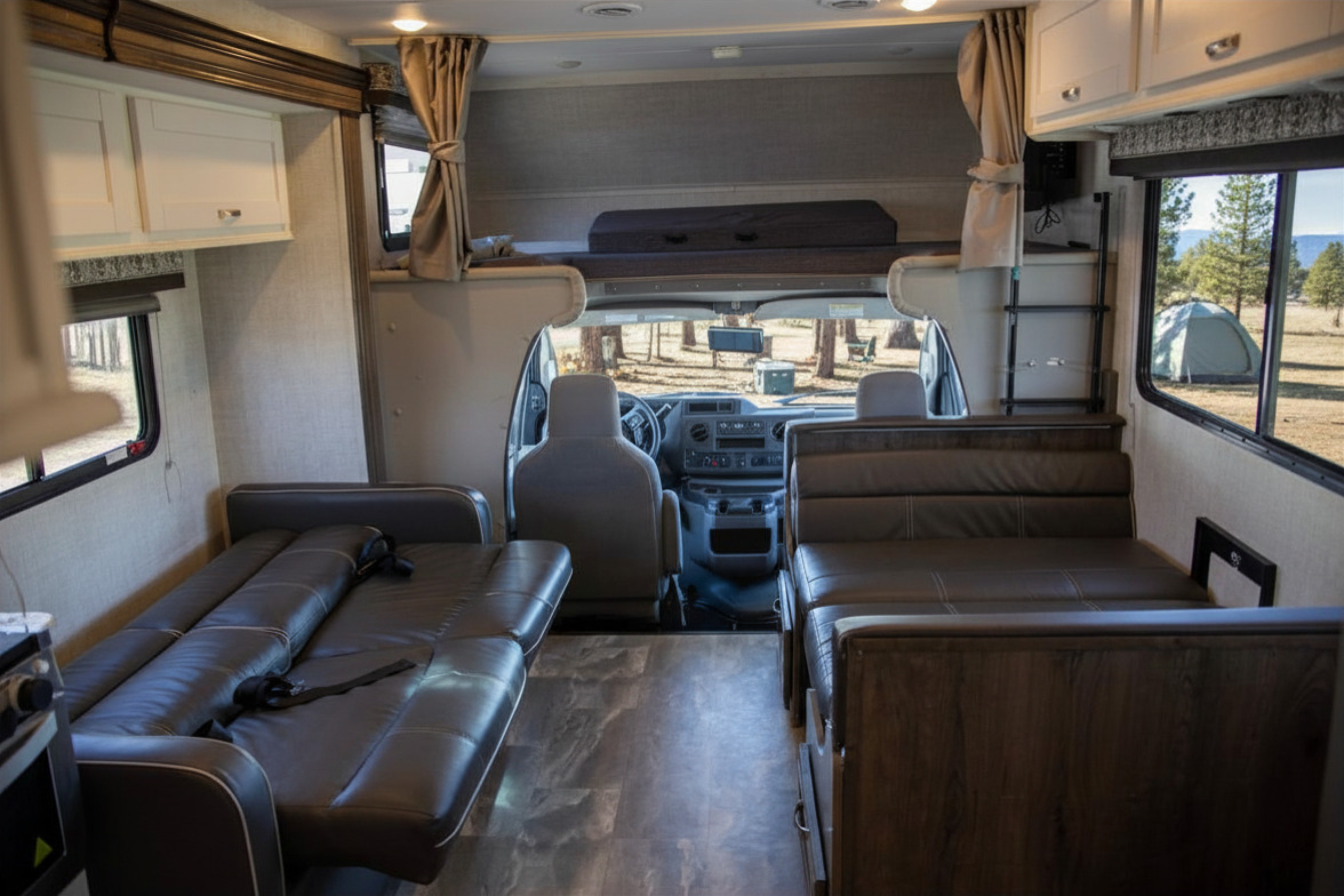 Spacious rv rental interior featuring comfortable seating, overhead bunk, and driver's cabin. Ideal for travel.. Gulf Stream Conquest 2022