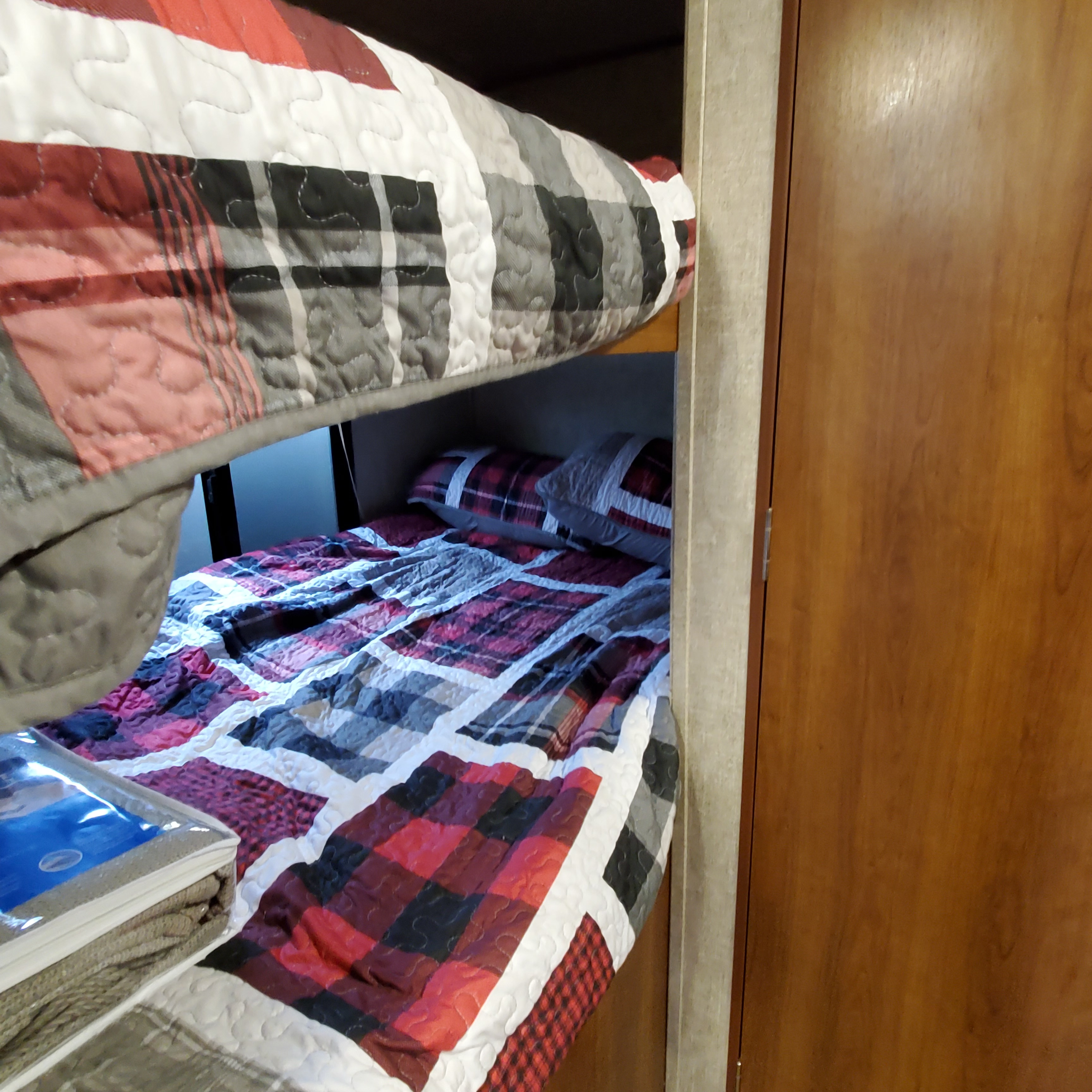 RV rental interior with bunk beds featuring cozy red & black plaid quilted bedding, a comfortable sleeping space.. Avenger ATI 2017