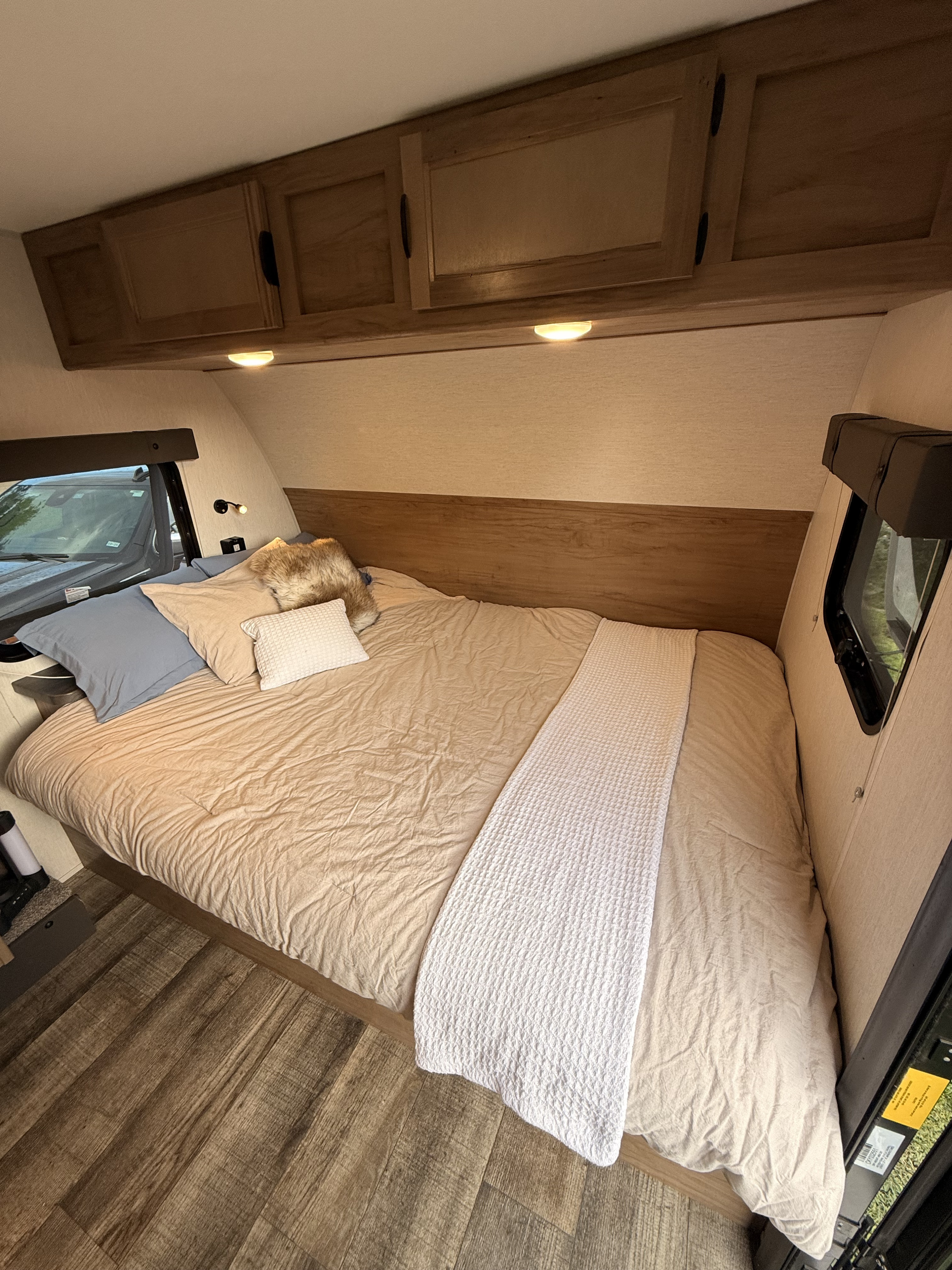 Cozy RV rental bedroom with warm bedding, overhead storage, and wood-look flooring for a comfortable stay.. Forest River Cherokee Wolf Pup Black Label 2024