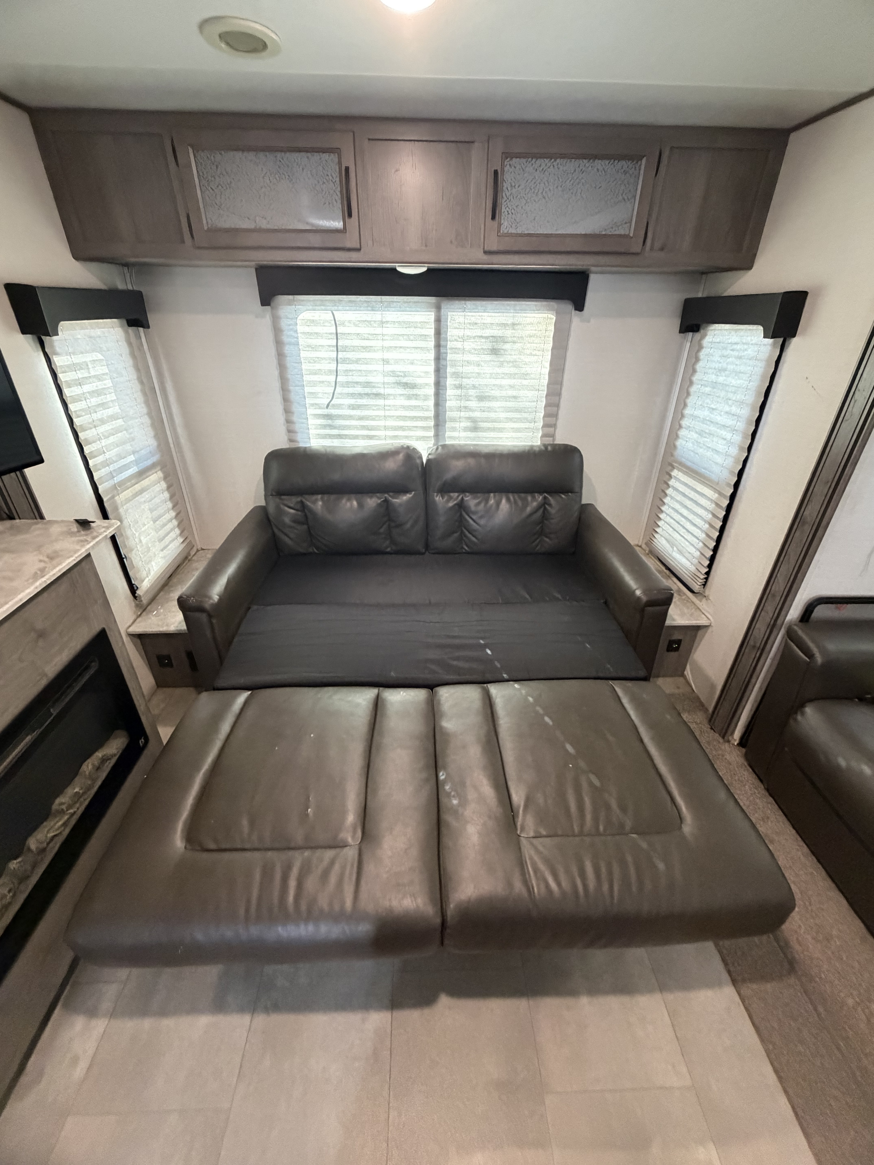 RV rental: Dark brown leather sofa converts to a bed. Overhead cabinets & fireplace add to this comfortable living space.. Coachmen Apex 2021