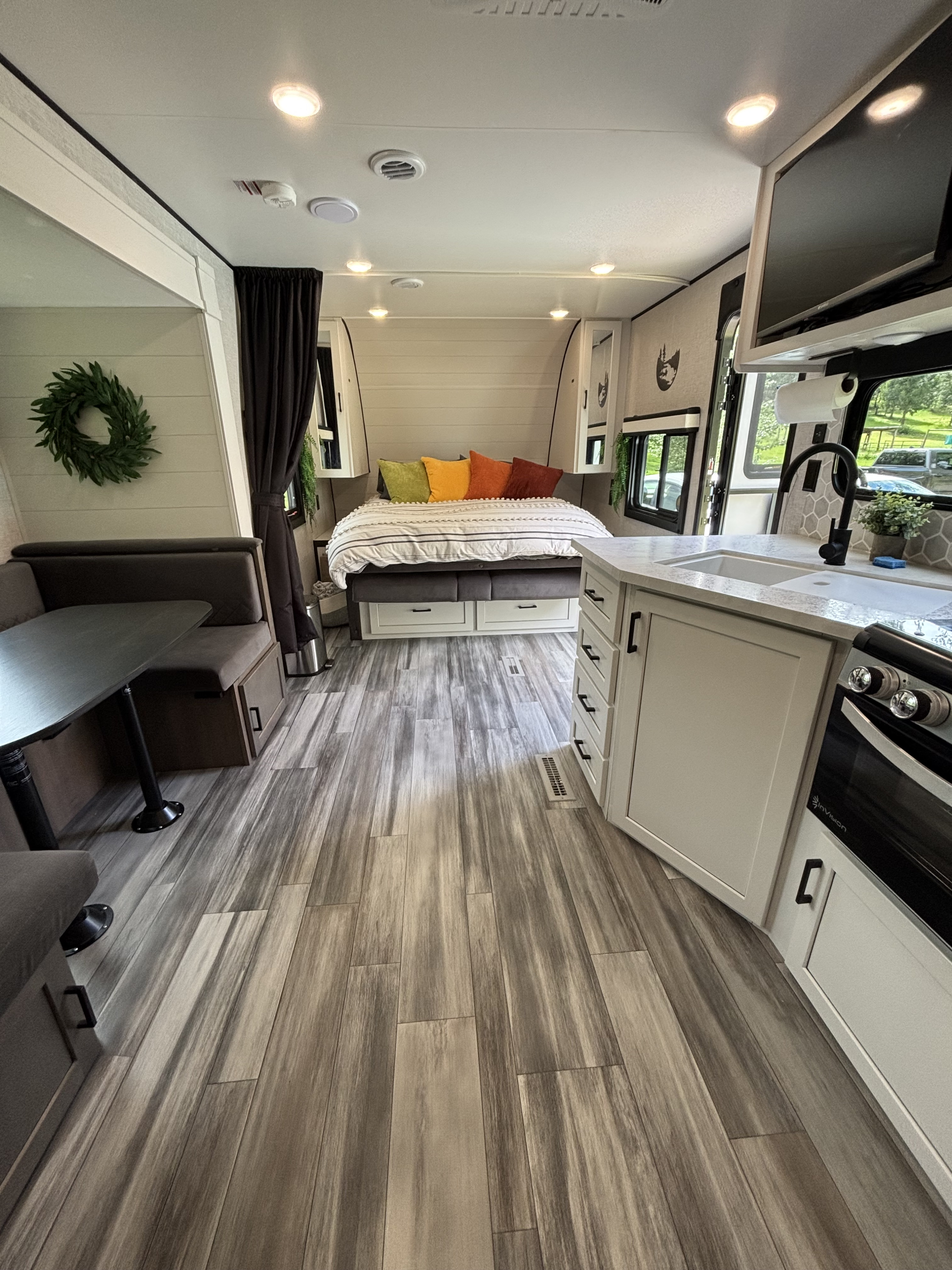 Spacious rv rental interior showing a cozy bedroom, kitchen with sink, and dinette. Light-toned wood-look flooring ties it together.. Jayco Jay Flight Bungalow 2025