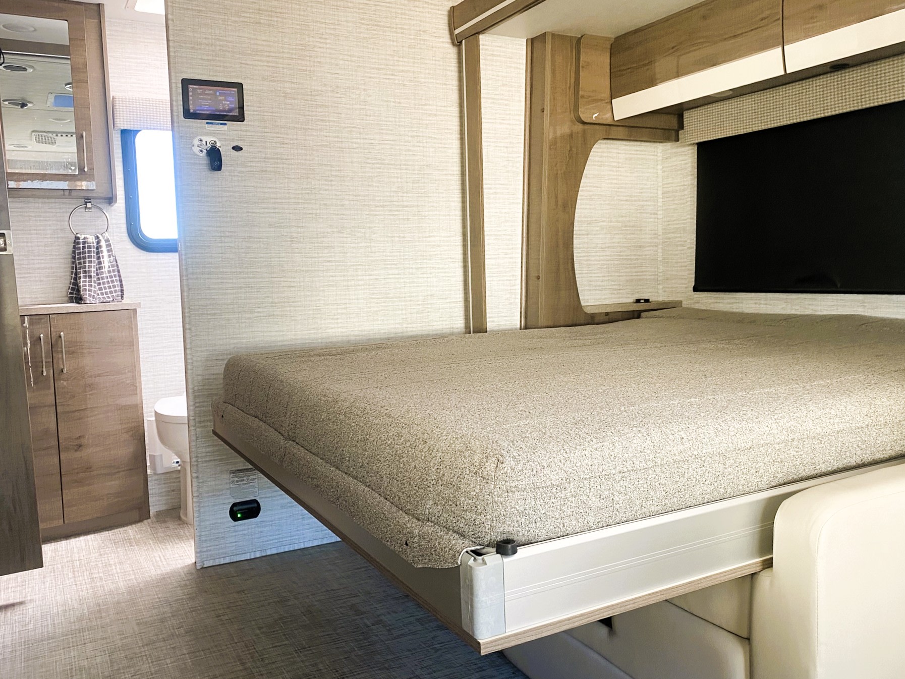 RV rental: Bright interior featuring a space-saving drop-down bed over a seating area, wall control panel, and bathroom.. Entegra Coach Qwest 2026