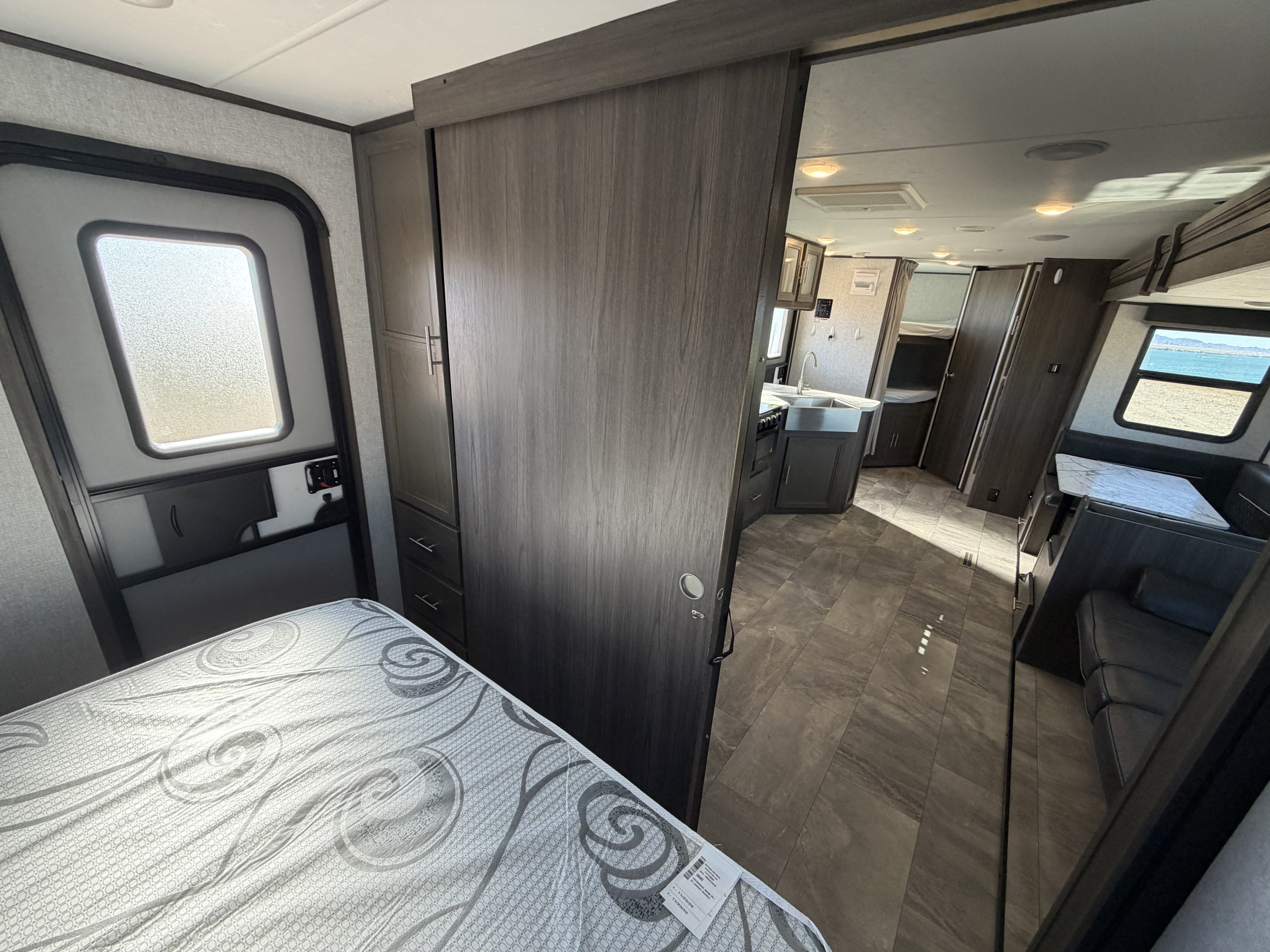 Modern RV rental interior: bedroom, sliding door to kitchen, dining area, and a scenic window view.. Dutchmen Kodiak Ultra Lite 2021