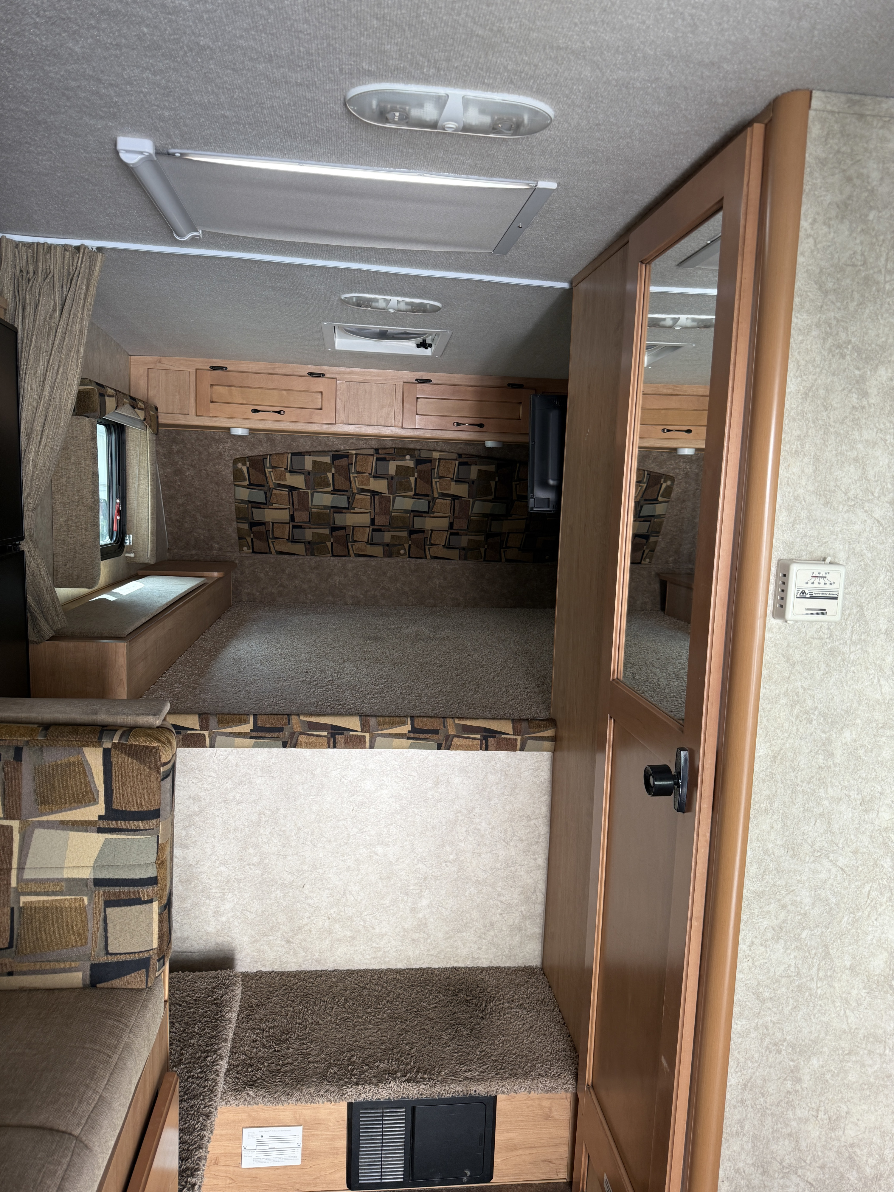 RV rental interior: elevated sleeping area with patterned headboard, overhead cabinets, and a step to the main living space.. Adventurer Lp Adventurer 2016