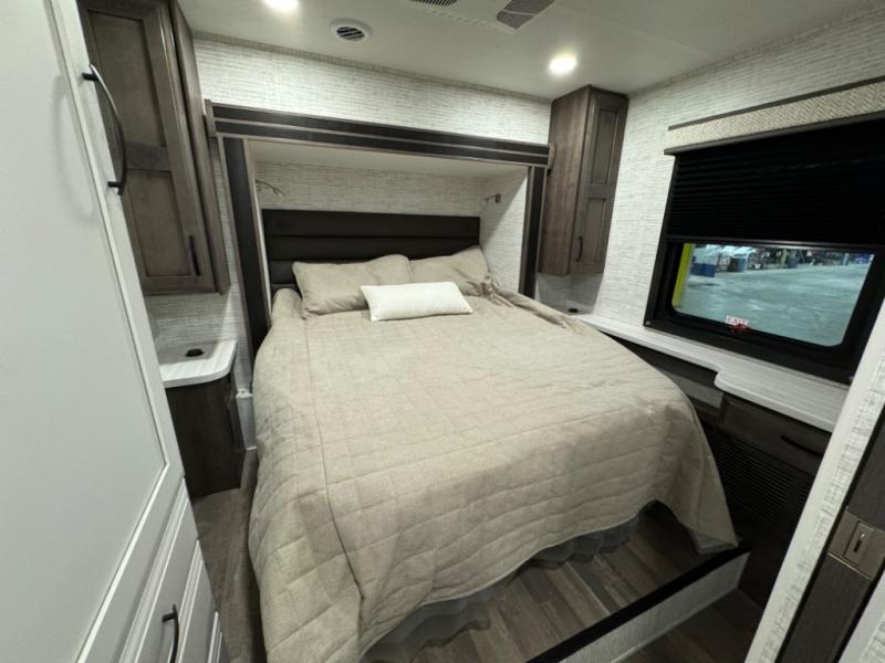 Cozy RV rental bedroom featuring a queen bed, modern wood cabinetry, and a large window. Perfect for comfortable travel.. Entegra Coach Odyssey 2025