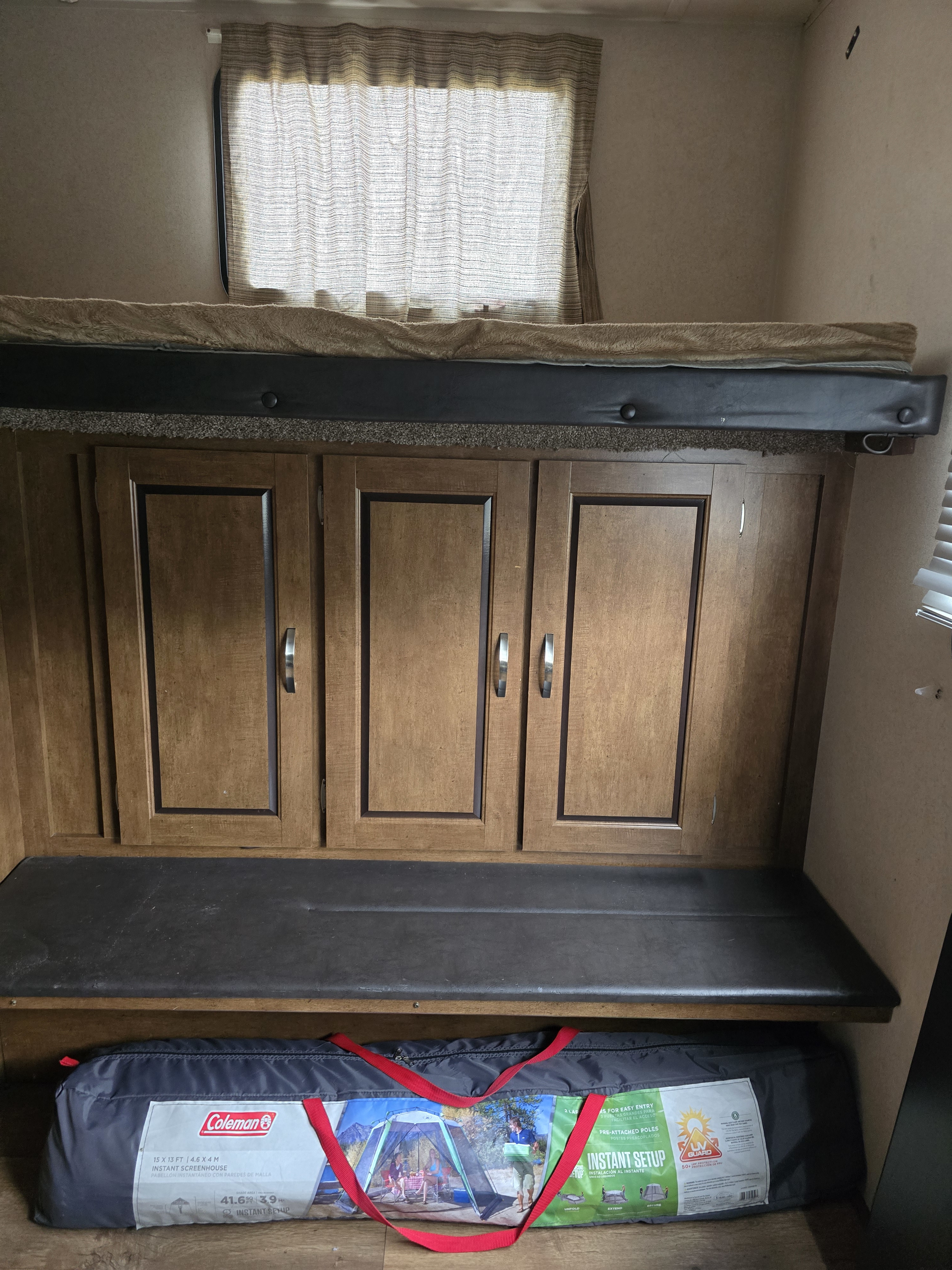 Cozy RV rental bunk area with wooden cabinets, a padded bench, and a Coleman screenhouse packed for outdoor fun.. Forest River Salem 2017