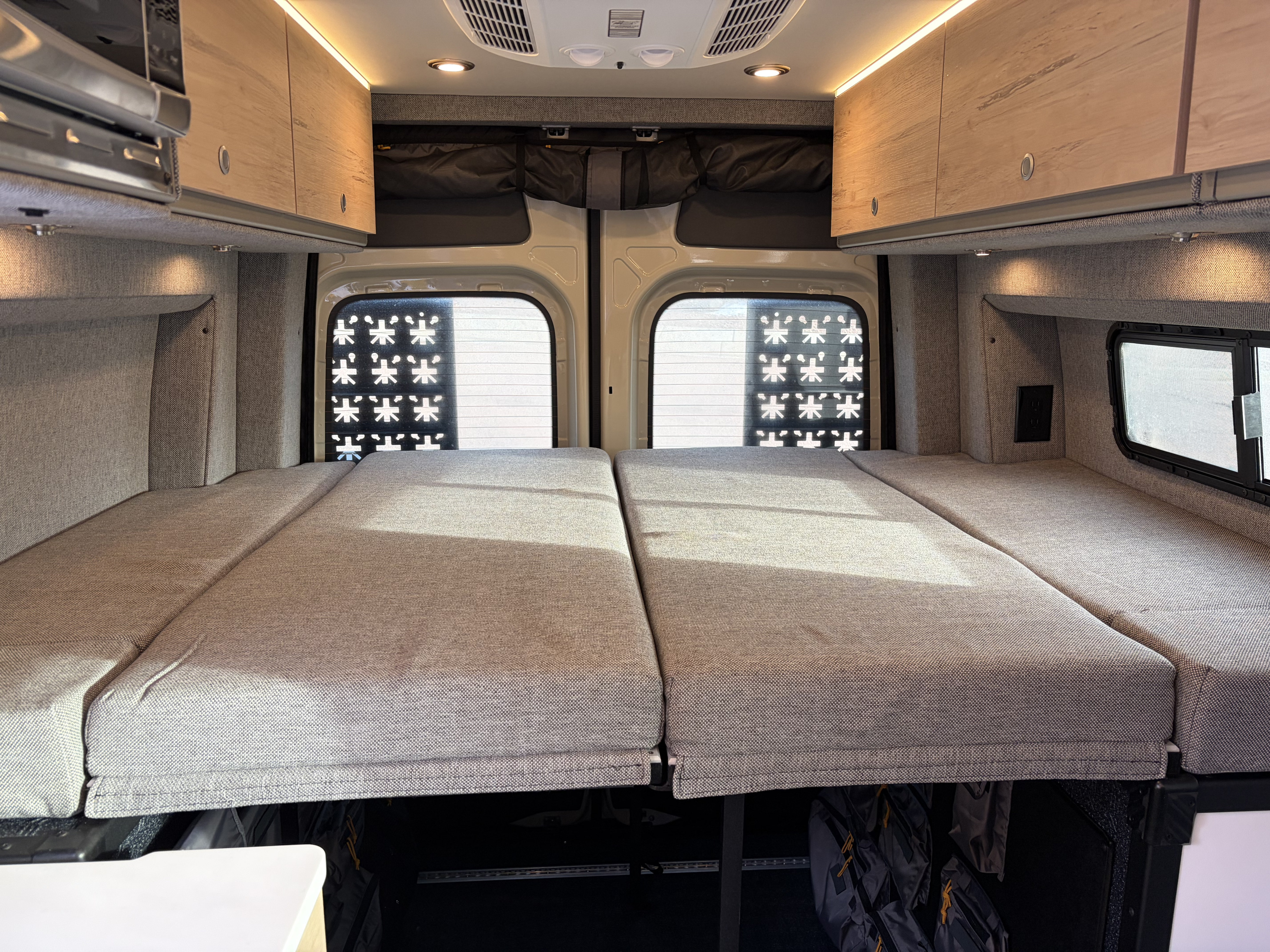 RV rental interior: a plush bed, overhead cabinets with lighting, microwave, and under-bed storage for your travels.. Mercedes MB 212 Sprinter 2025