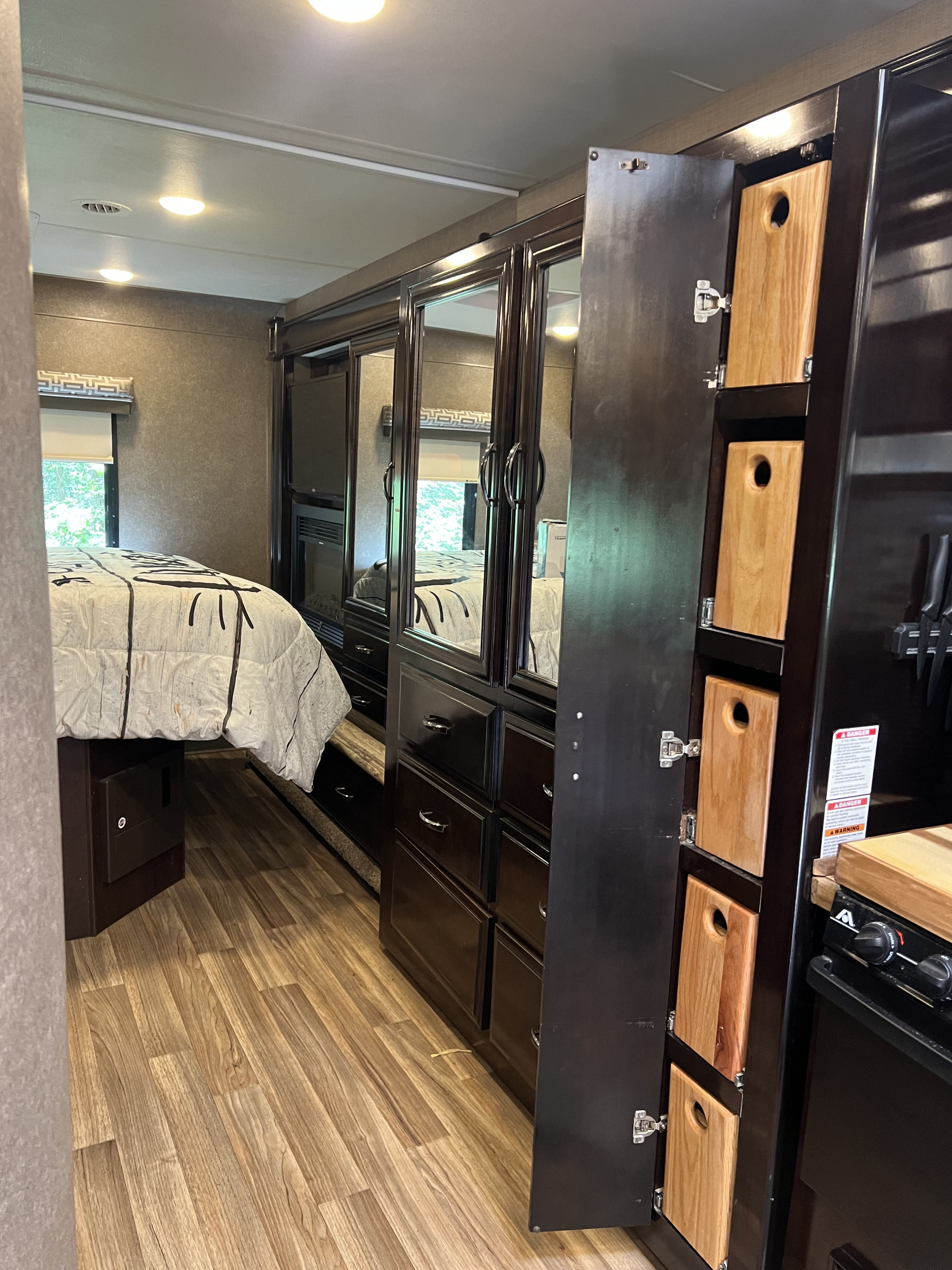 RV rental: Modern interior featuring a bed, dark wood cabinets, and clever kitchen storage with vertical cutting boards.. Thor Quantum 2017