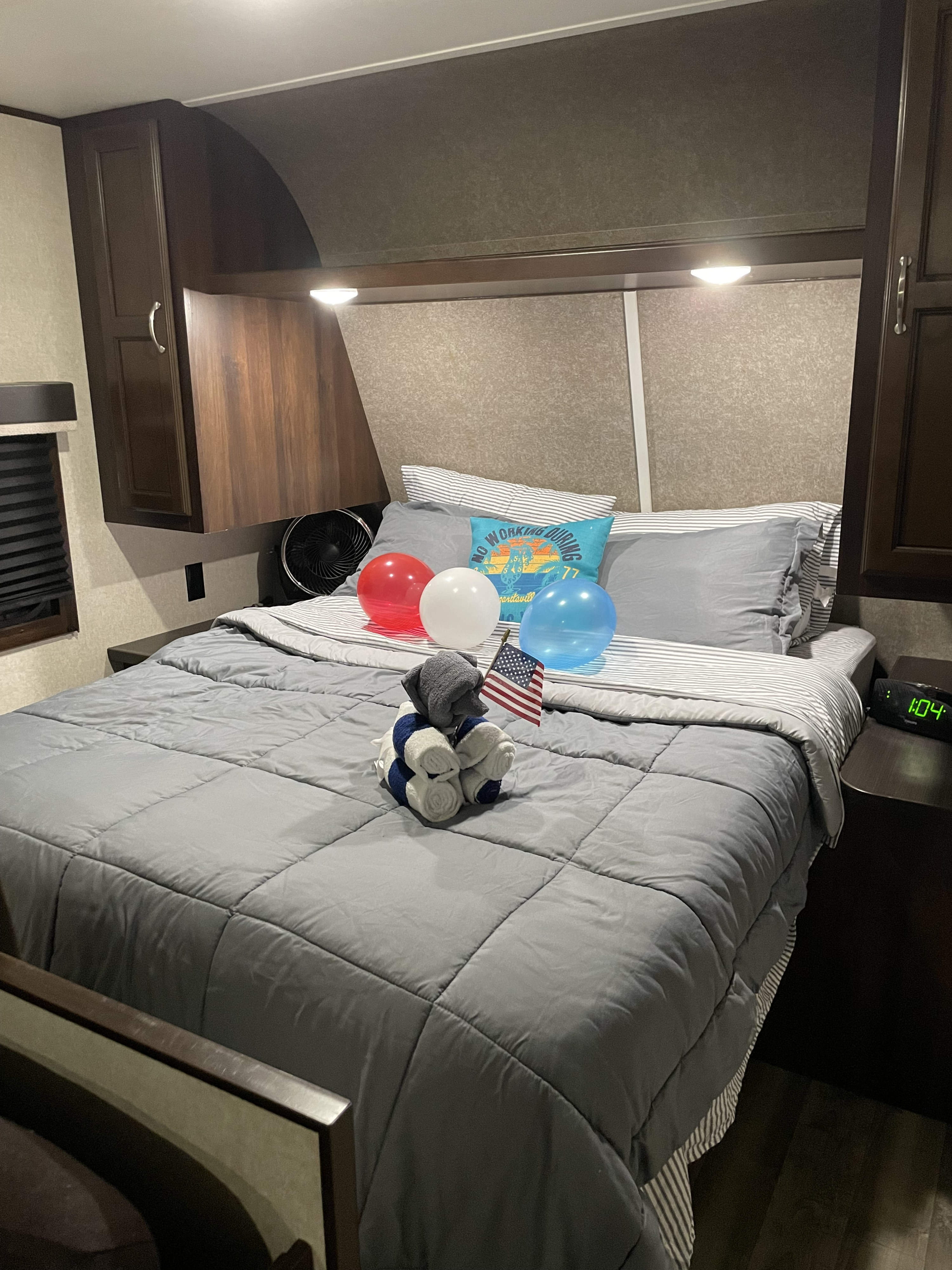 Inside an RV rental, a decorated bedroom features a bed with grey comforter, RWB balloons, a US flag, and towel art.. Jayco Jay Flight SLX 2018