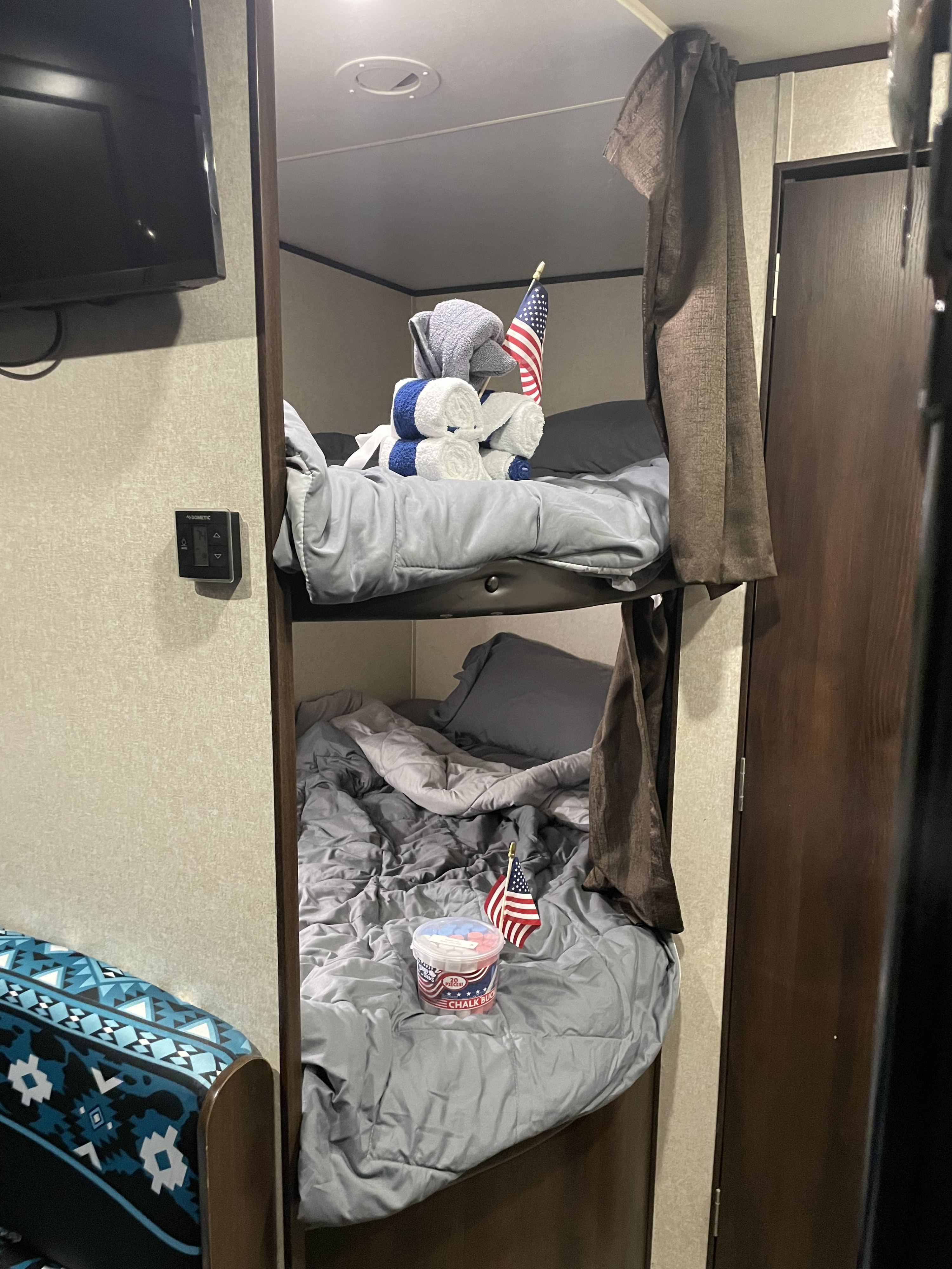 Inside an RV rental: two bunk beds with gray bedding, an American flag on each, and decorative towels on the top bunk.. Jayco Jay Flight SLX 2018