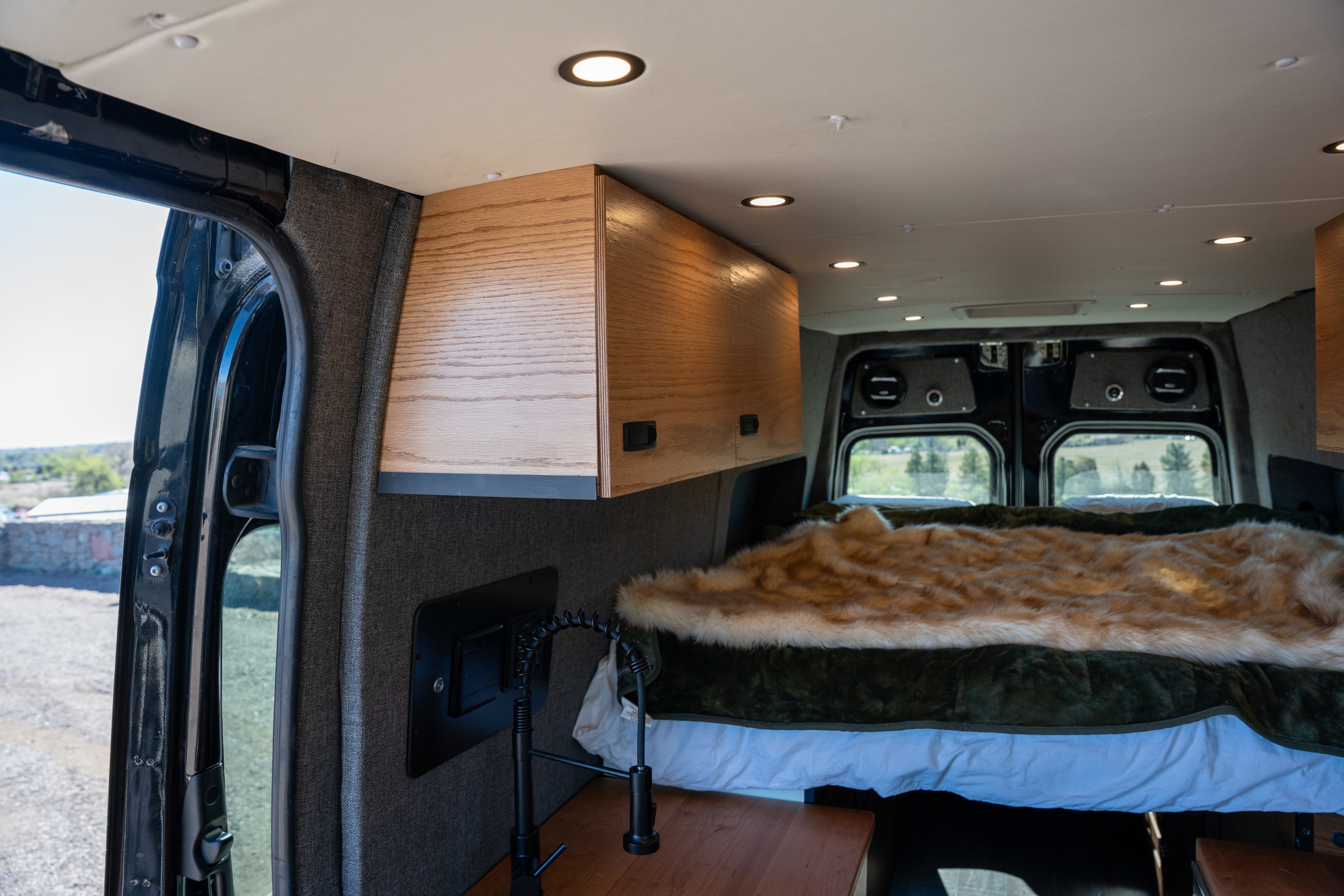 Step into this cozy rv rental featuring a plush bed, wooden cabinets, and recessed lighting for your van life adventure.. Mercedes-Benz Sprinter 2015