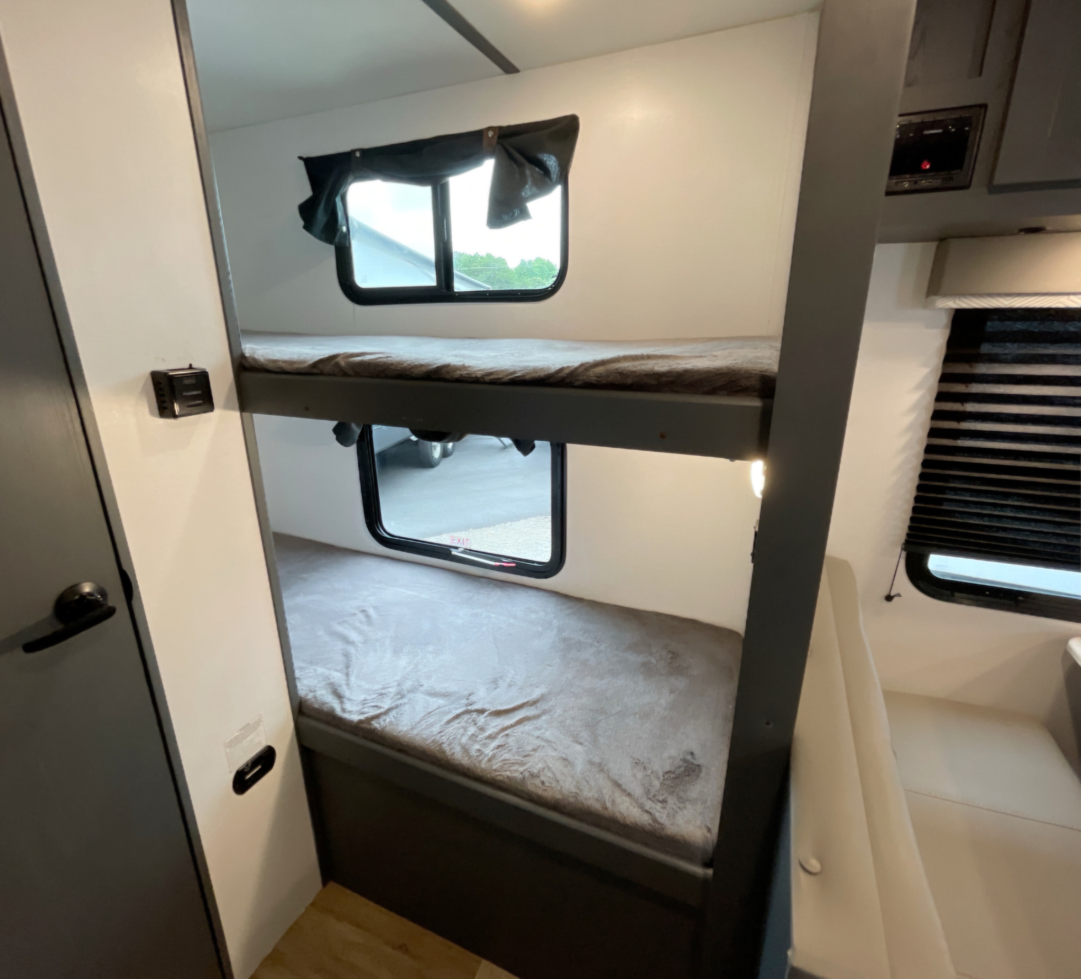 Two-tier bunk beds with windows and comfortable bedding inside an RV rental, ideal for family trips and adventures.. Keystone RV Bullet Crossfire 2022