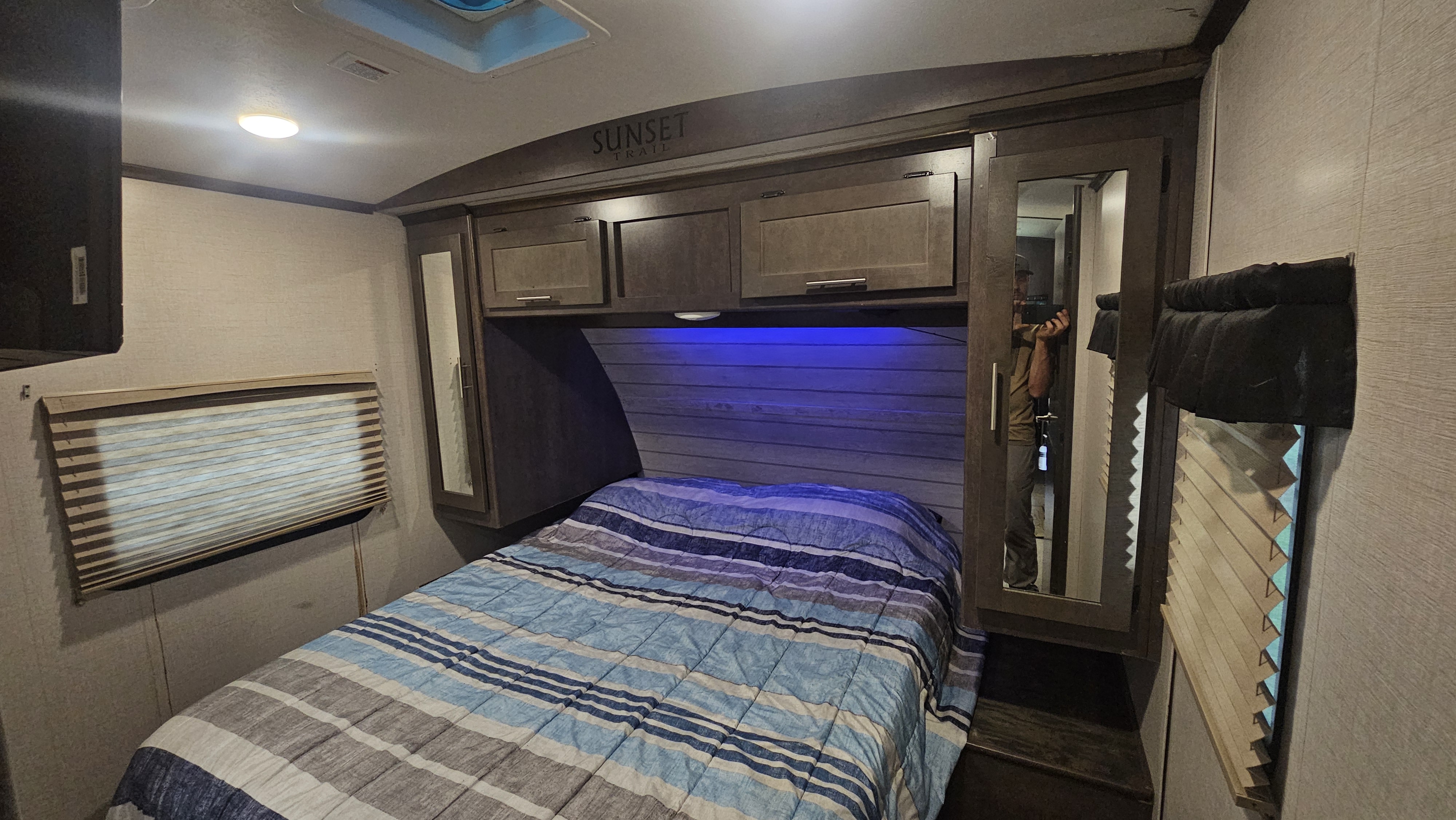 Sunset Trail RV rental bedroom with striped bed, overhead storage, and blue mood lighting. Ready for your adventure.. Crossroads RV Sunset Trail Super Lite 2018