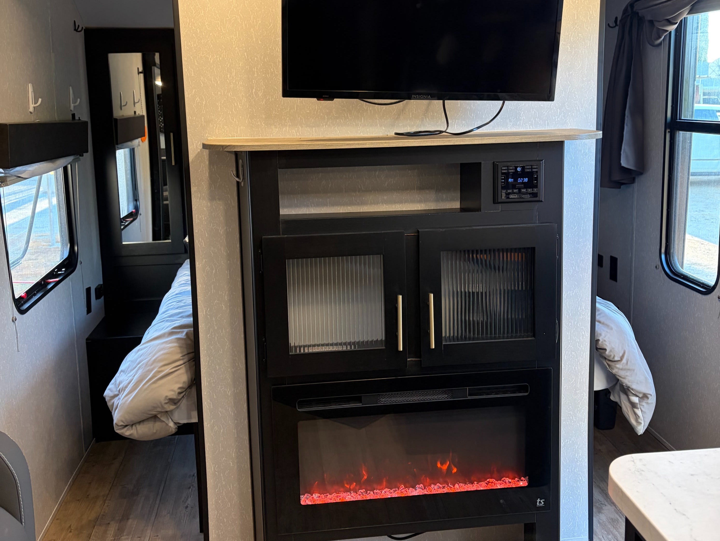 RV rental interior: TV, stereo, and electric fireplace entertainment center, with a peek into a cozy, compact bedroom.. Forest River Cherokee Grey Wolf 2022