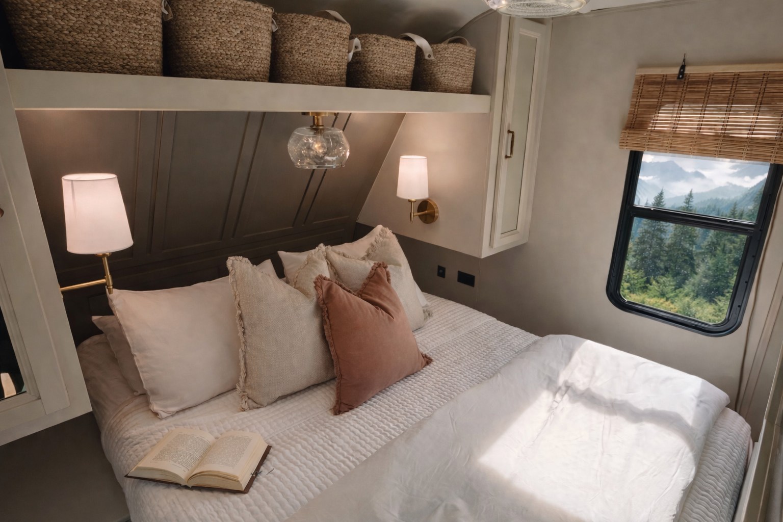 Cozy RV rental bedroom. A plush bed with neutral pillows and an open book, bathed in soft light, overlooks a mountain view.. Highland Ridge RV Open Range 2022