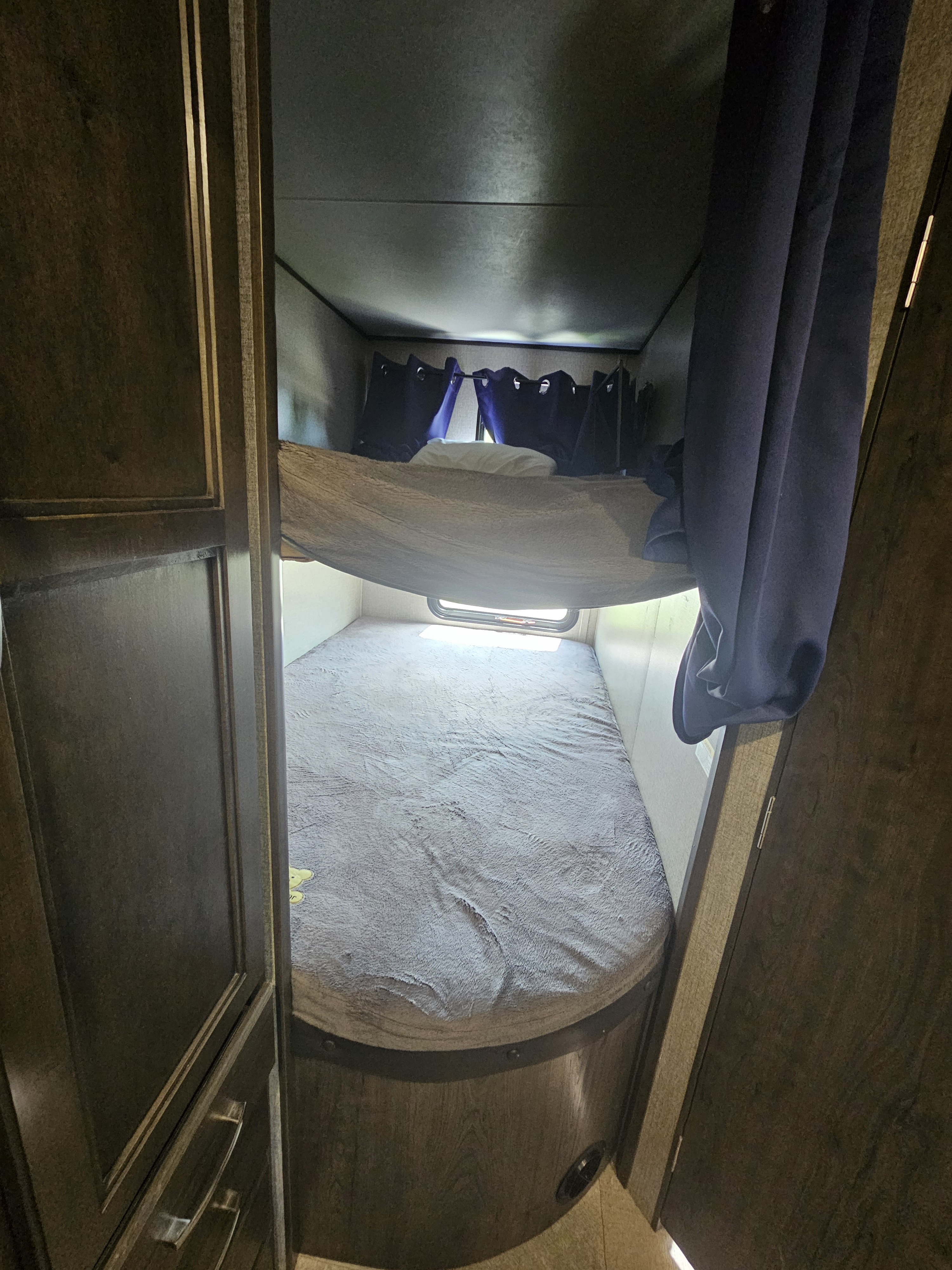 Inside an RV rental: two cozy bunk beds with gray blankets and curtains, providing comfortable sleeping for a family.. Jayco Jay Flight SLX 2020