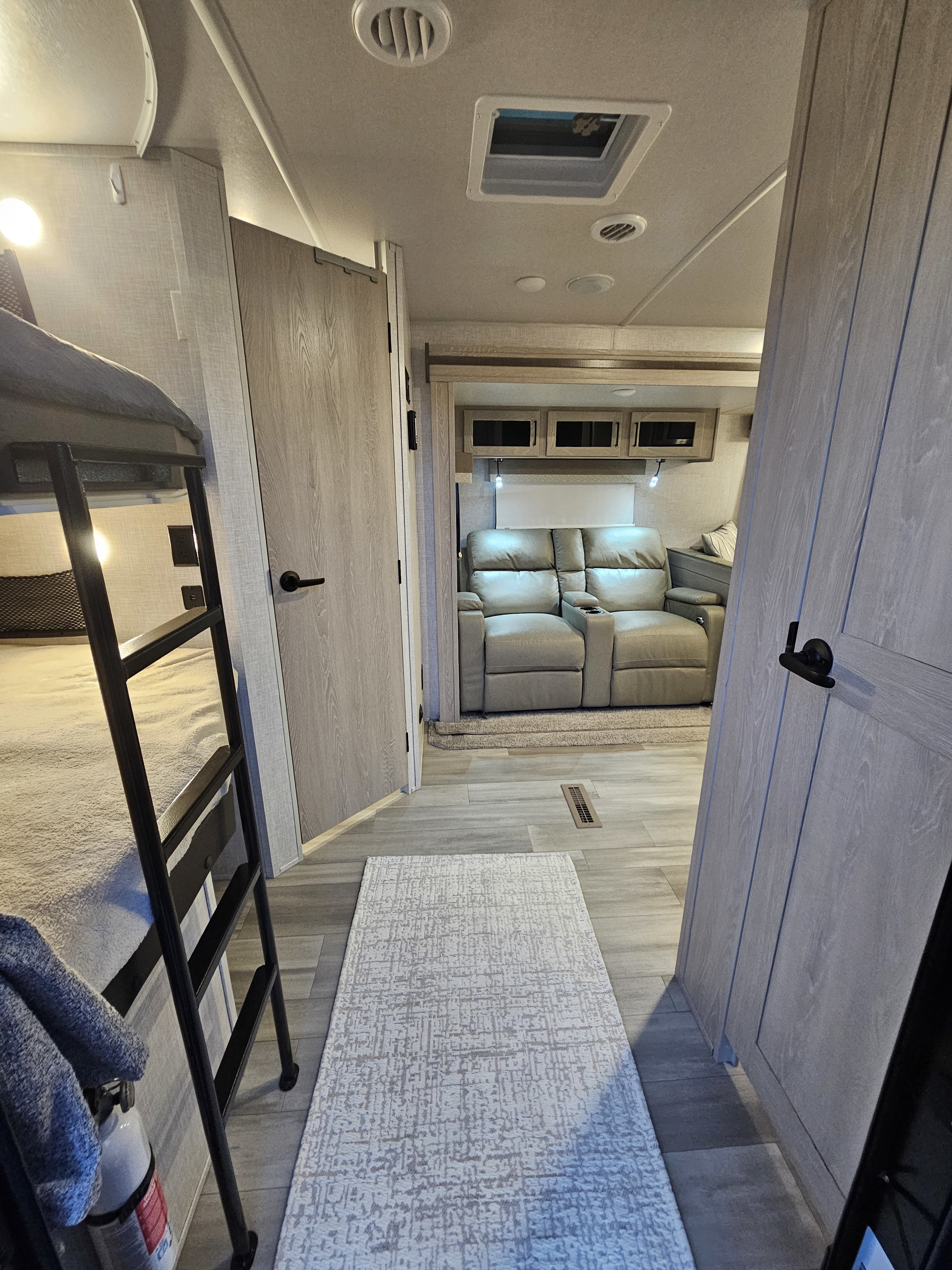 RV rental interior: bunk beds, recliners, and hallway with rug. A comfortable, well-lit mobile living space.. Forest River Flagstaff Super Lite 2022