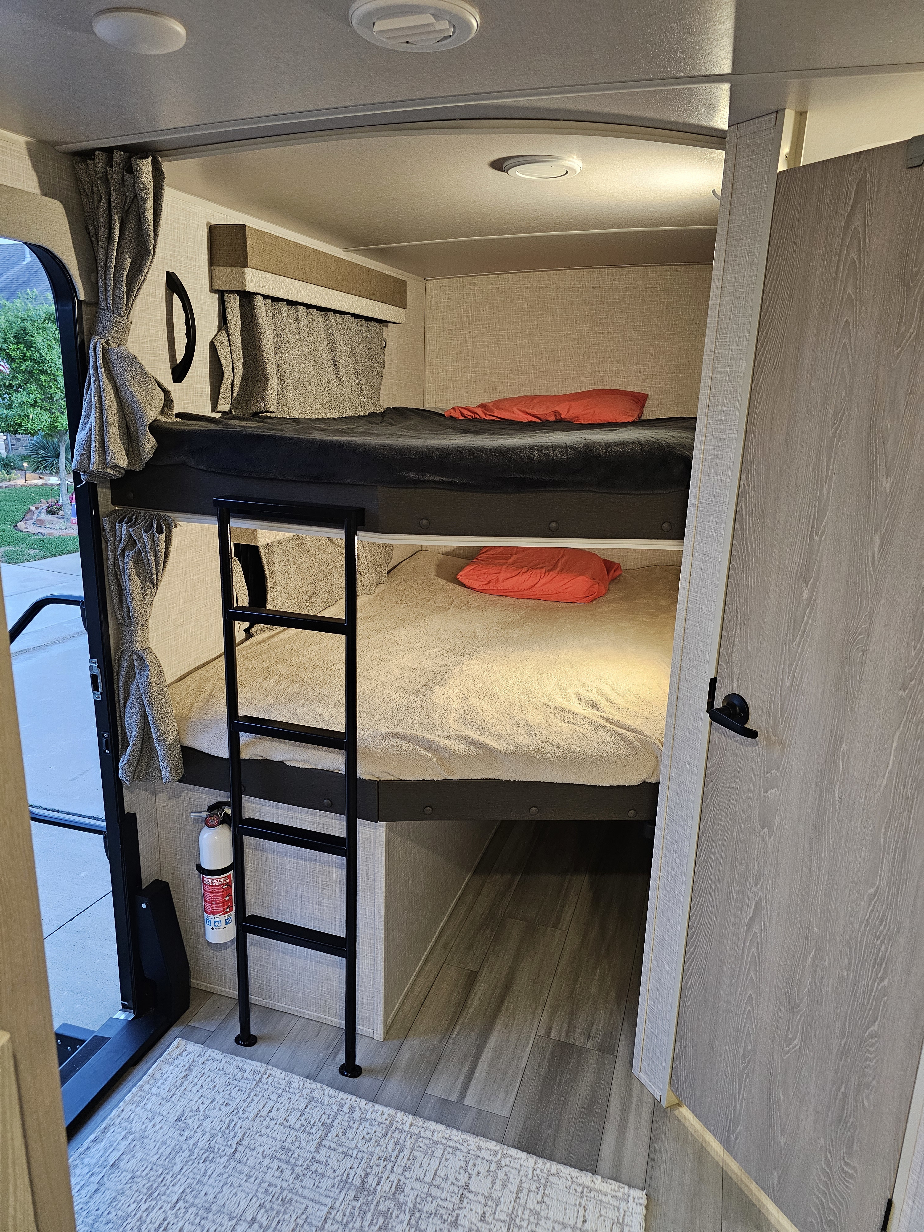 Cozy bunk beds with a ladder in this rv rental. Soft blankets, red pillows, and a fire extinguisher are visible inside.. Forest River Flagstaff Super Lite 2022