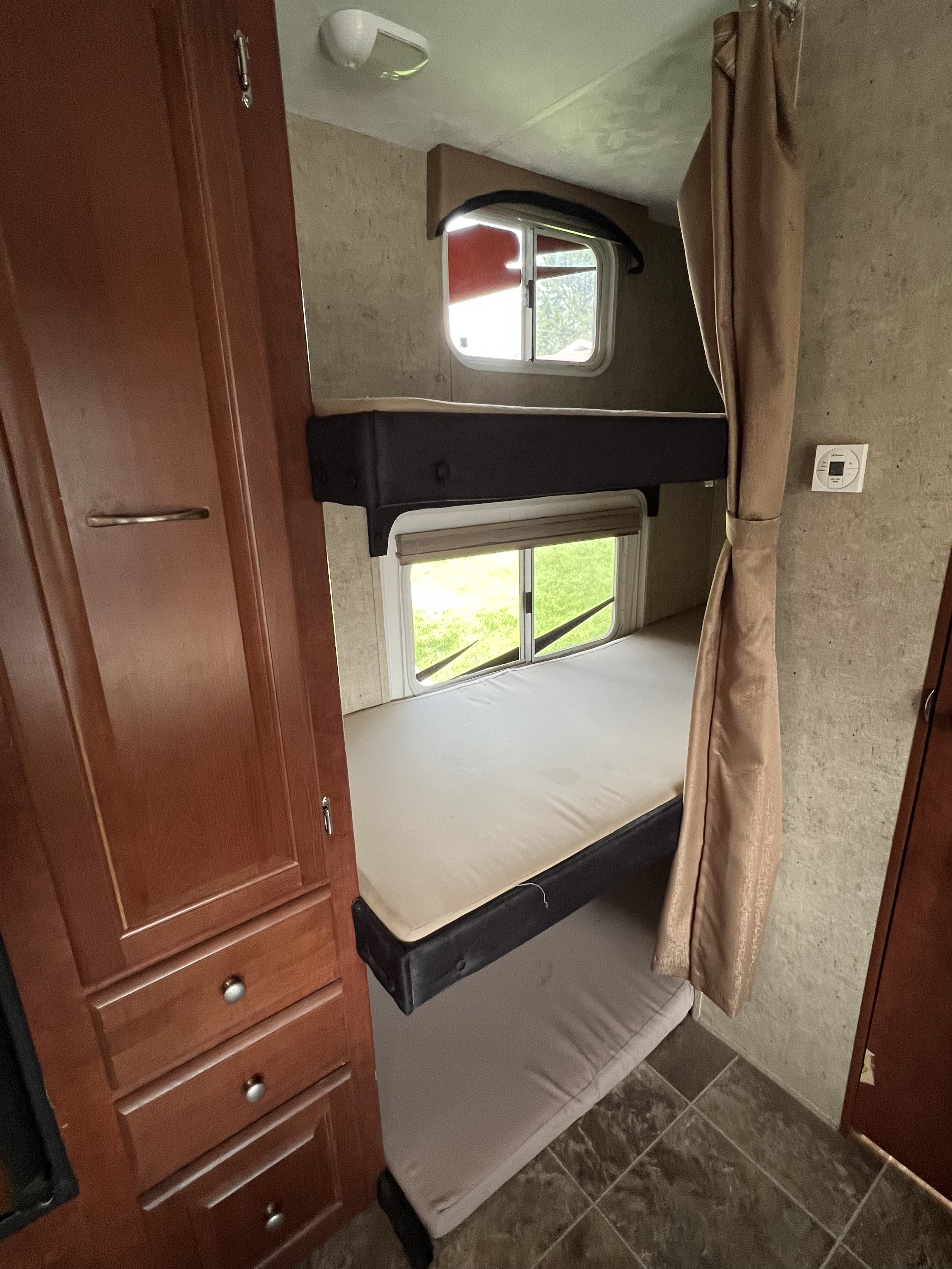 Inside this **rv rental**: a set of comfortable bunk beds with windows, a closet, and thermostat. Ideal for family adventures.. Forest River Wildwood 2012
