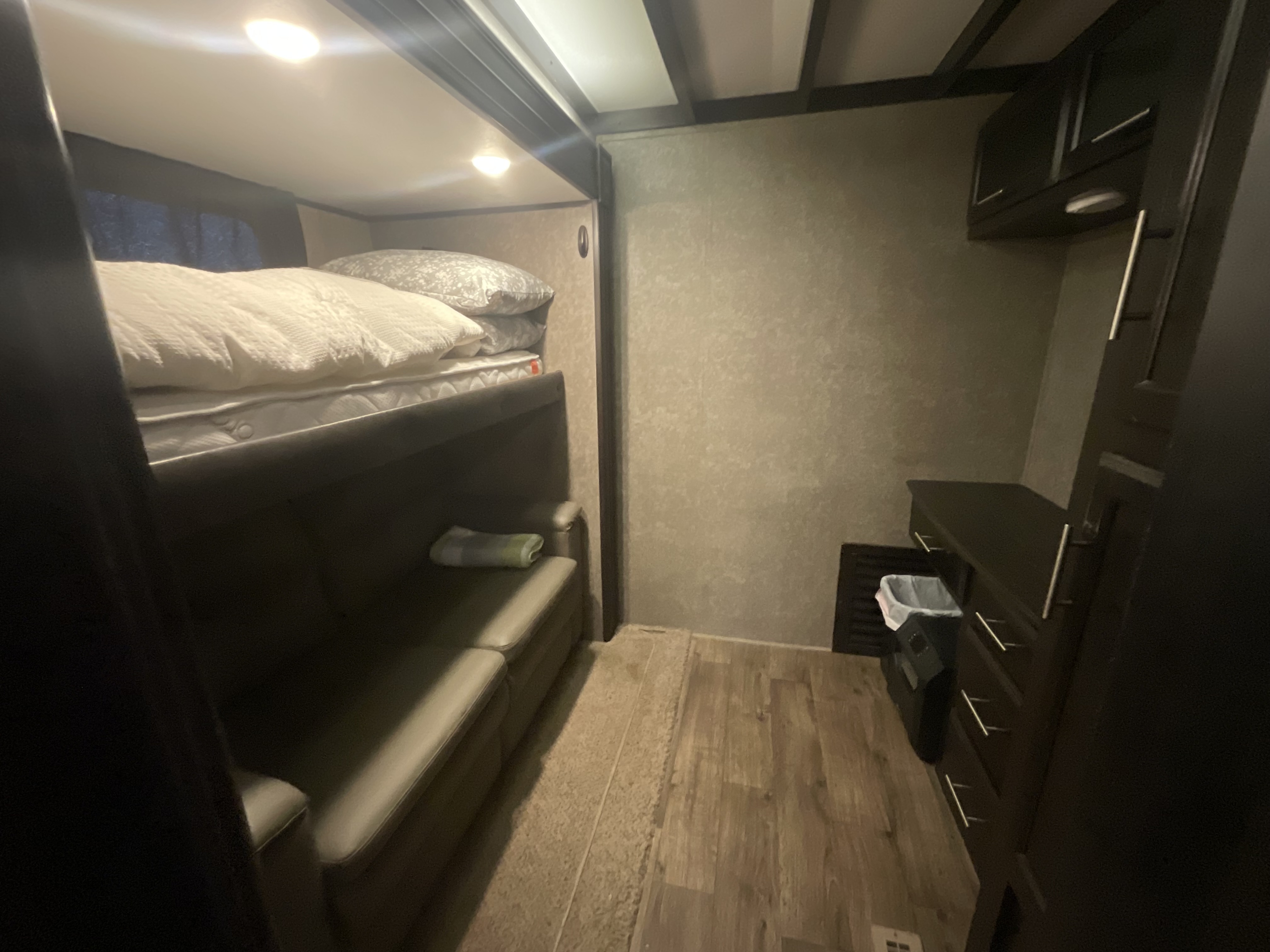Explore the compact and functional bunk bedroom of this rv rental, with a comfy sofa, overhead lights, and storage drawers.. Jayco Eagle 2020