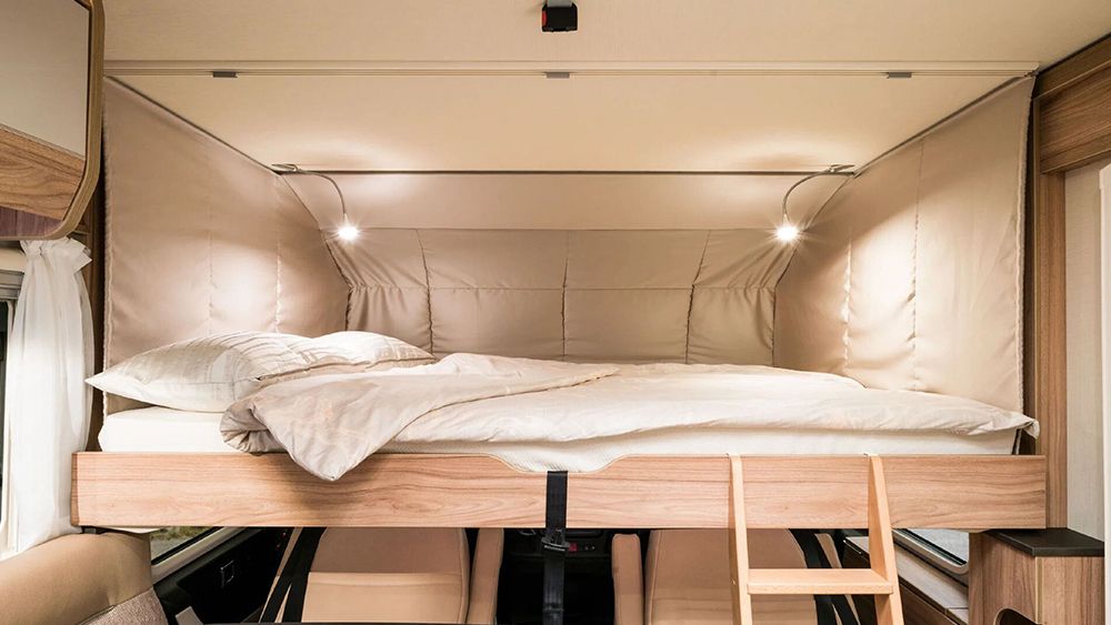 Get a great night's sleep in this RV rental's clever drop-down bed with cozy bedding and reading lights.. HYMER EXISIS I 474 2025