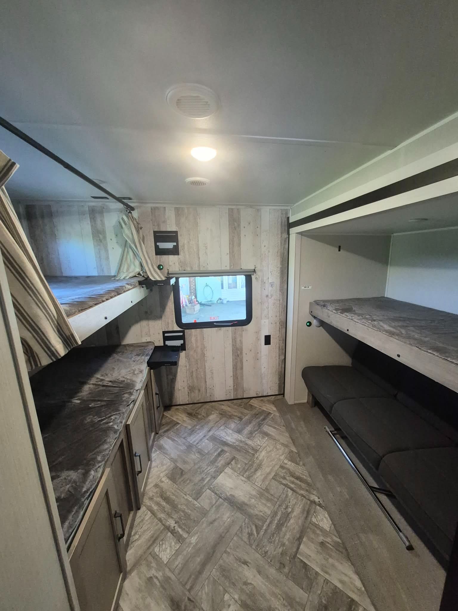 Modern RV rental bunkhouse interior: features multiple bunk beds, comfortable sofa seating, kitchen counter, and wood-look finishes.. palomino puma 2023