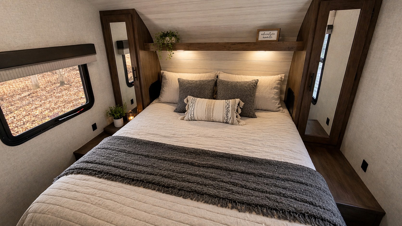 Cozy RV rental bedroom with a comfy bed, warm lighting, autumn window view, and mirrored wardrobe.. Forest River Wildwood X-Lite 2021