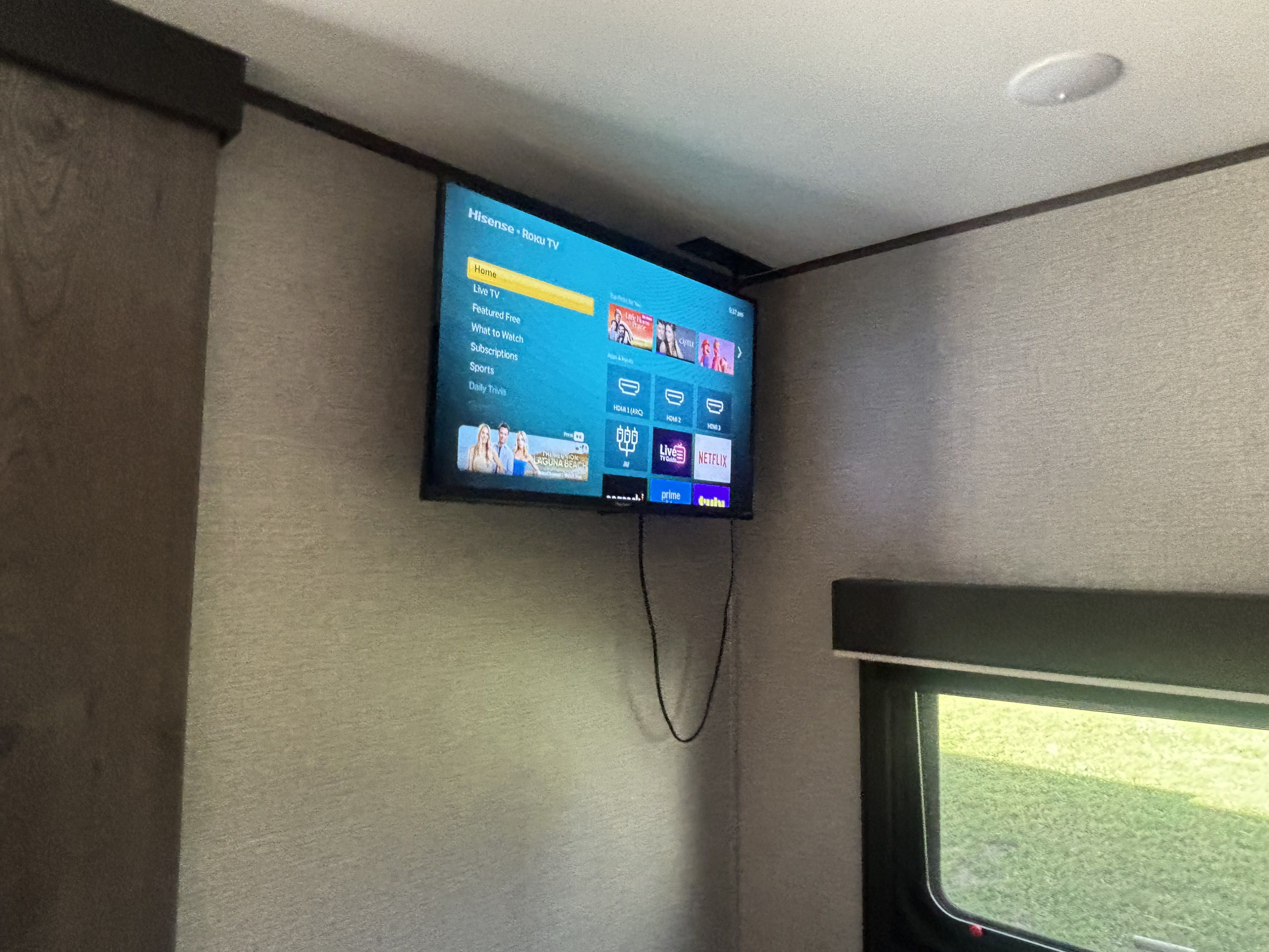 Inside an RV rental, a mounted Hisense Roku TV displays its home screen with various streaming options for entertainment.. Jayco Jay Flight 2020