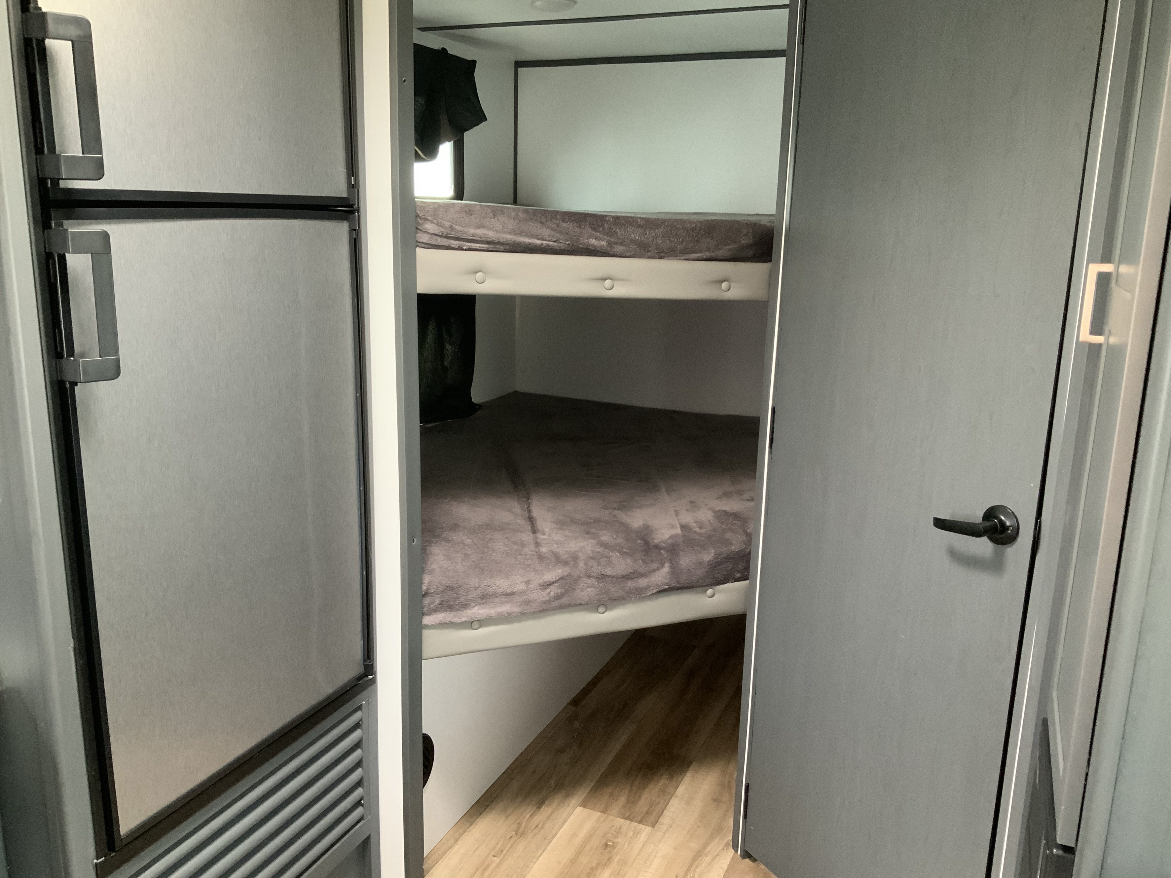 An rv rental interior featuring a refrigerator on the left and dual bunk beds on the right, designed for compact travel.. Keystone RV Bullet Crossfire 2022