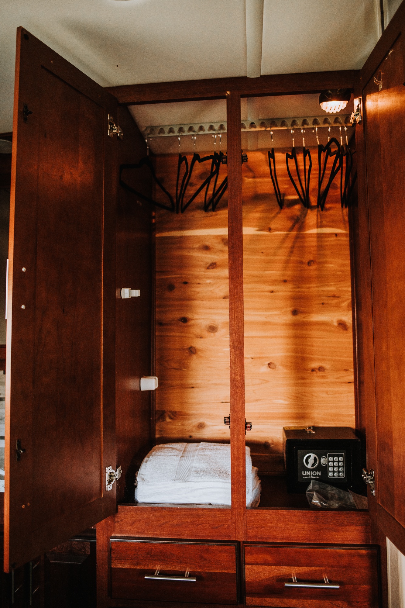 Inside an RV rental: Open wooden wardrobe with hangers, stacked towels, and a personal safe.. Forester Forester Motorhome 2014