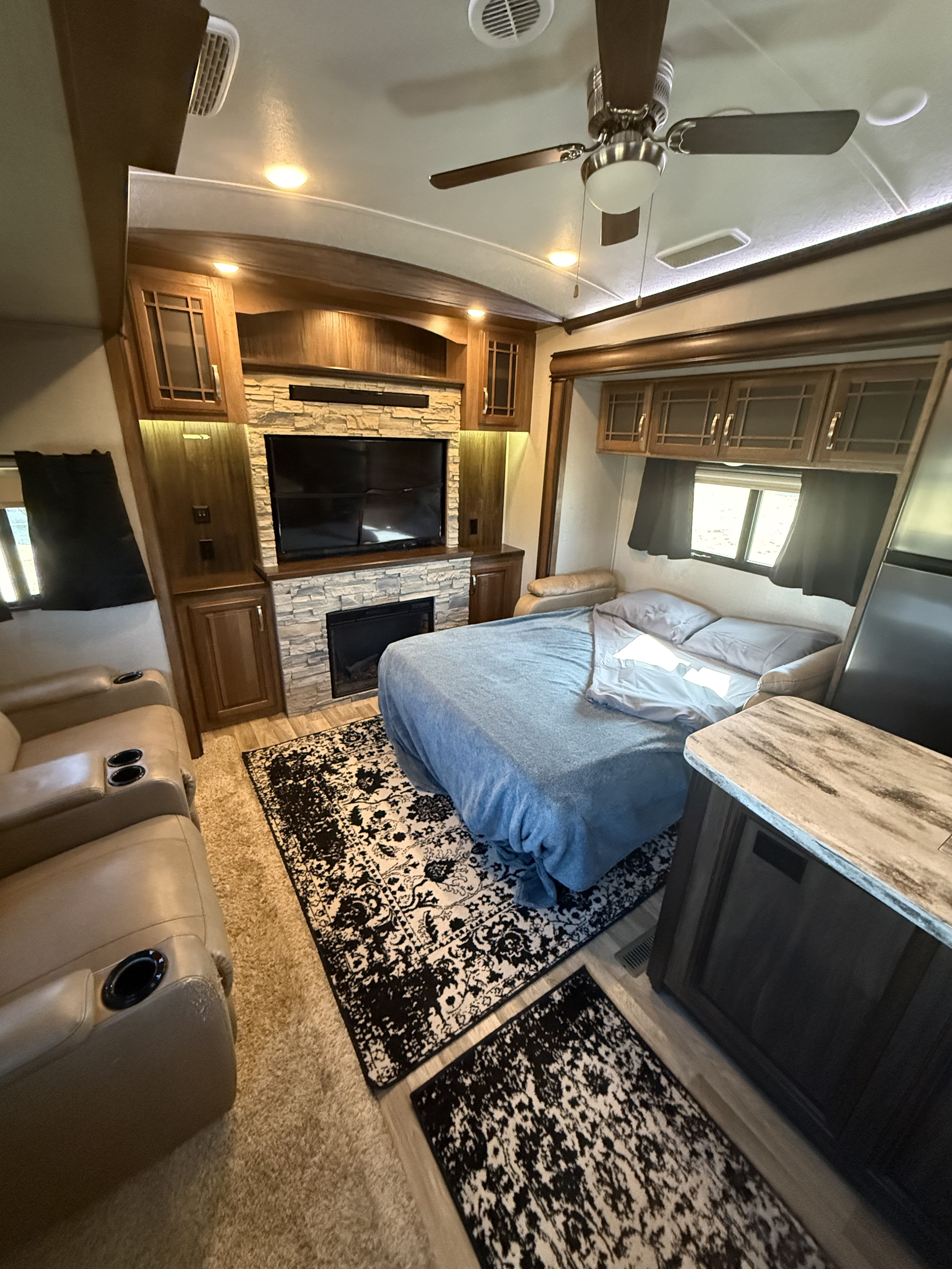Experience comfort in this RV rental featuring a cozy bed, stone fireplace, TV, and plush recliners, perfect for your travels.. Keystone RV Montana 2017