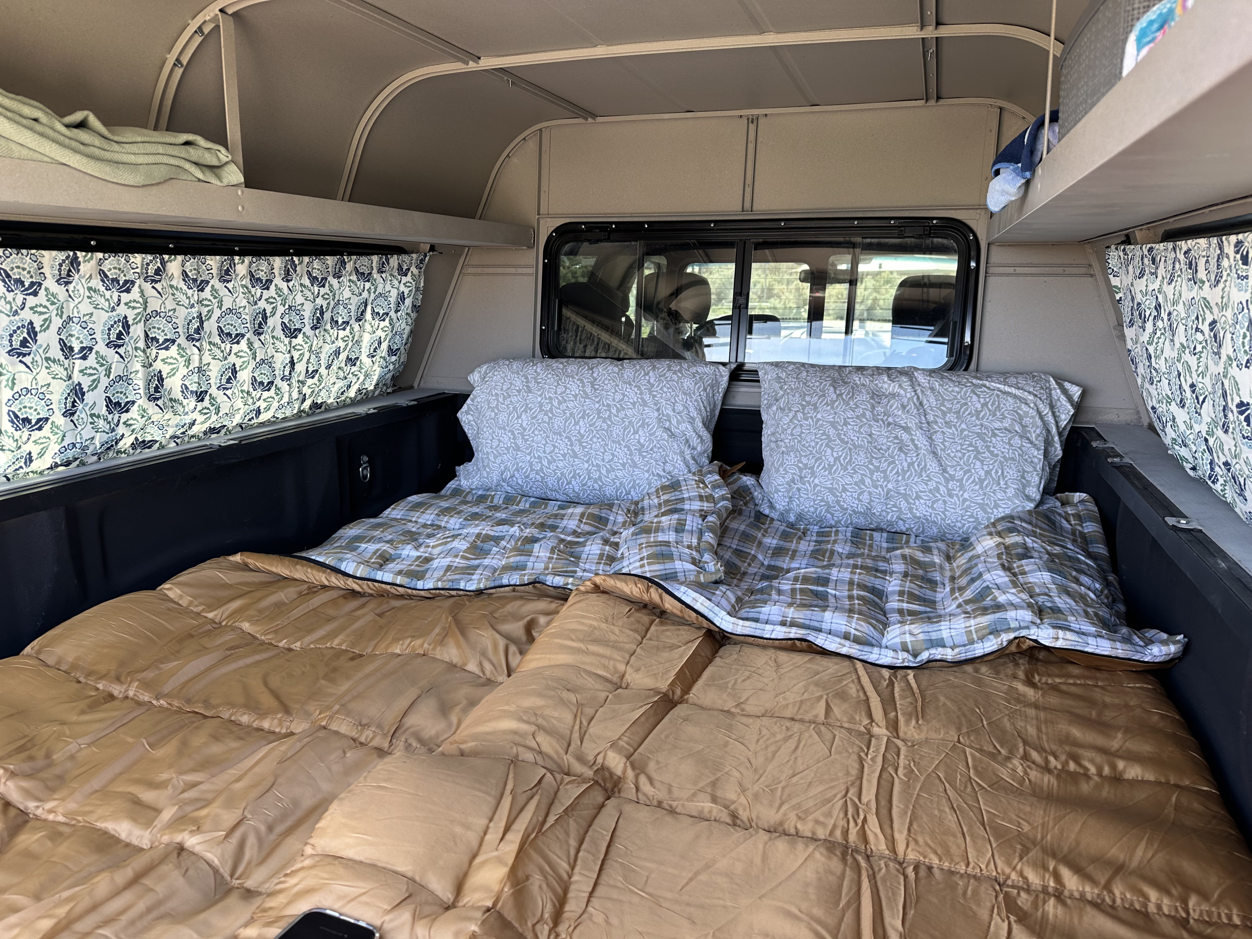 Cozy truck bed camper interior setup with sleeping bags, pillows, and curtains. Perfect for an RV rental adventure.. Ford Ford F150 2017