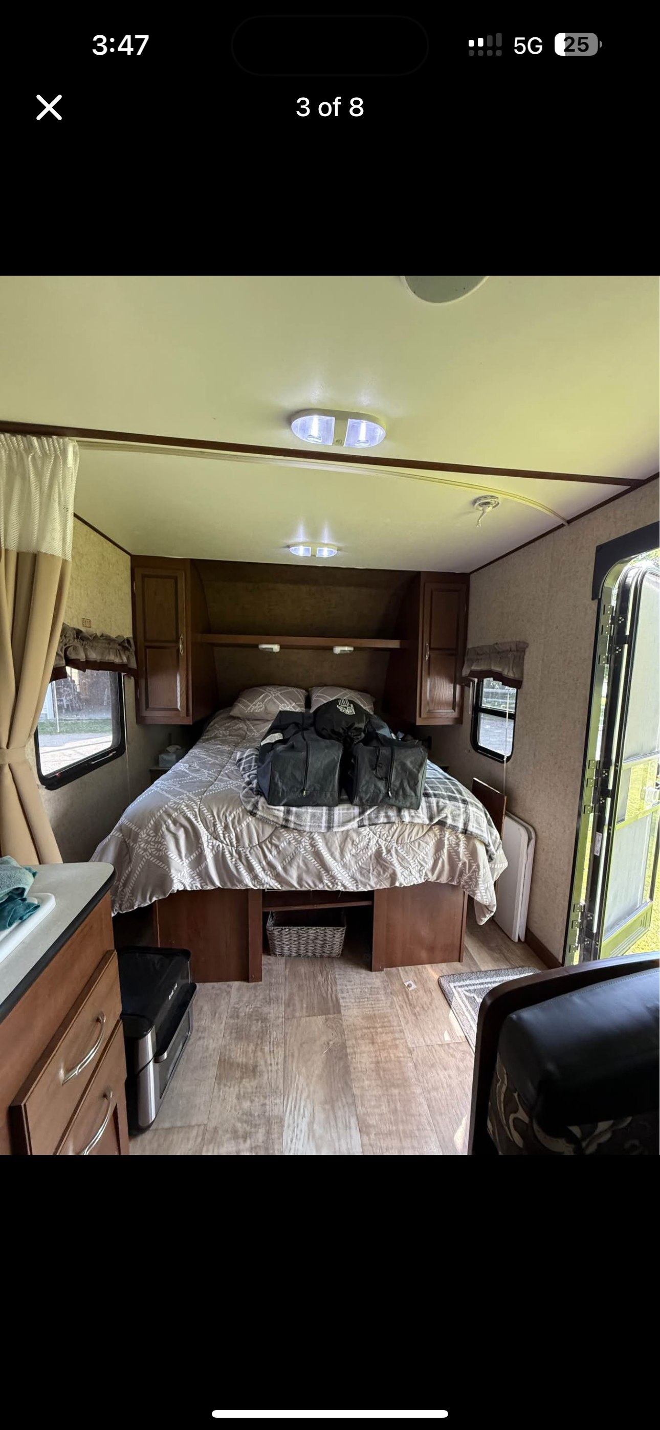 This RV rental features a cozy bedroom with a large bed, wood cabinets, side windows, and a bright, inviting interior.. Nomad Nomad Trailer 2016
