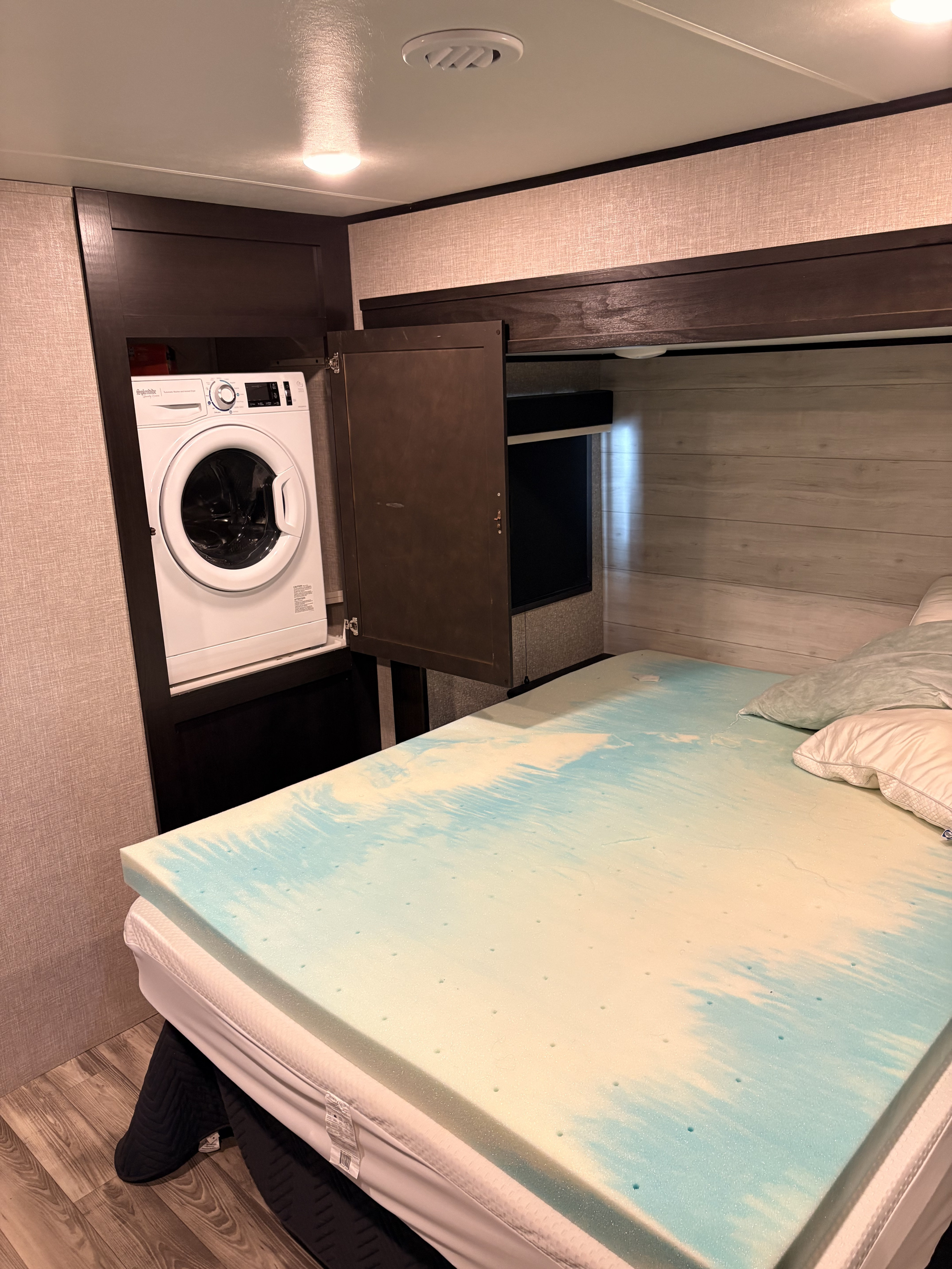 RV rental bedroom with a built-in compact washer, comfy memory foam topper bed, and integrated overhead storage.. Jayco Eagle HT 2023