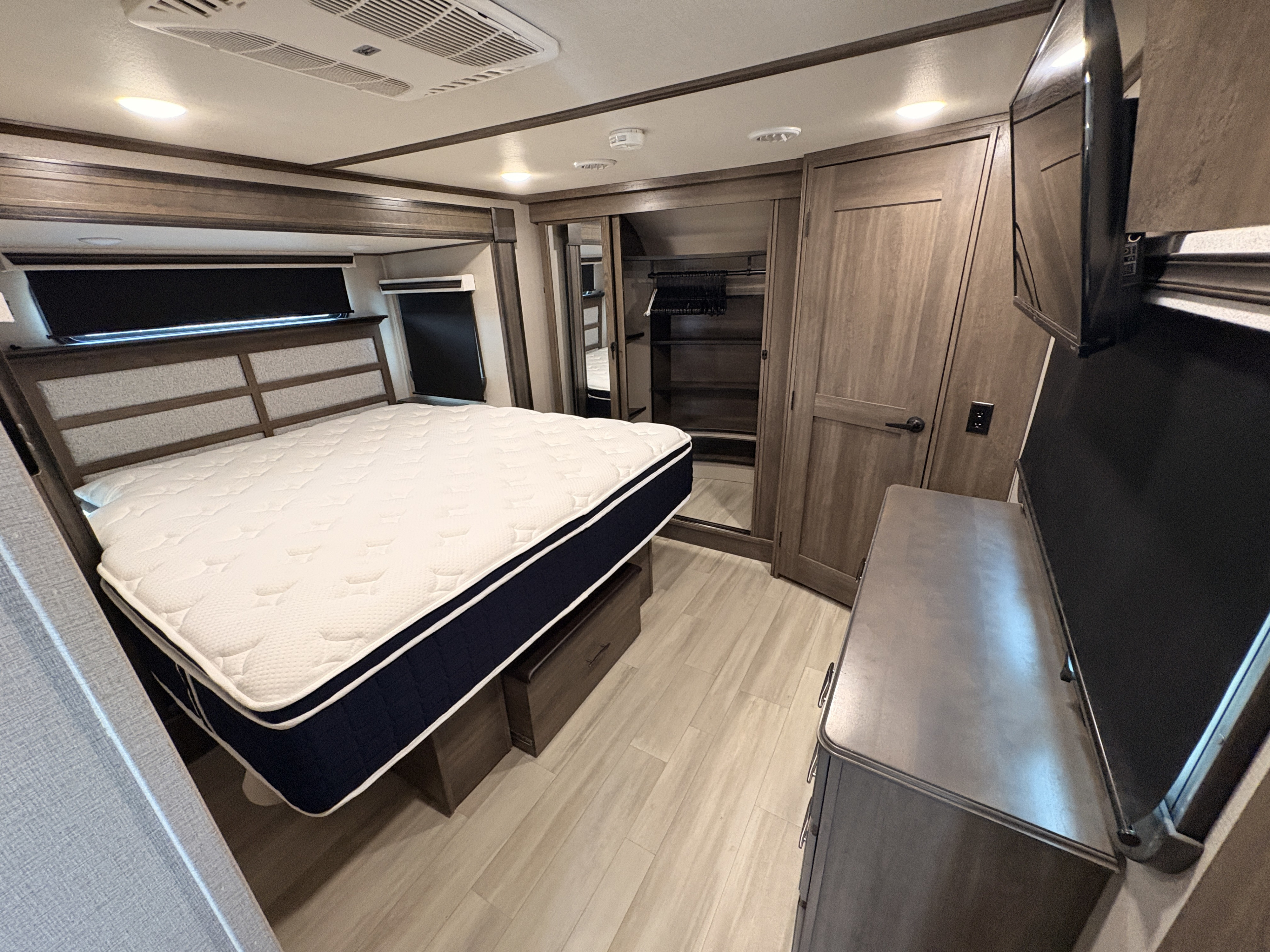 Modern RV rental bedroom with a comfortable bed, TV, and ample storage, ready for your next adventure.. Grand Design Solitude 2022