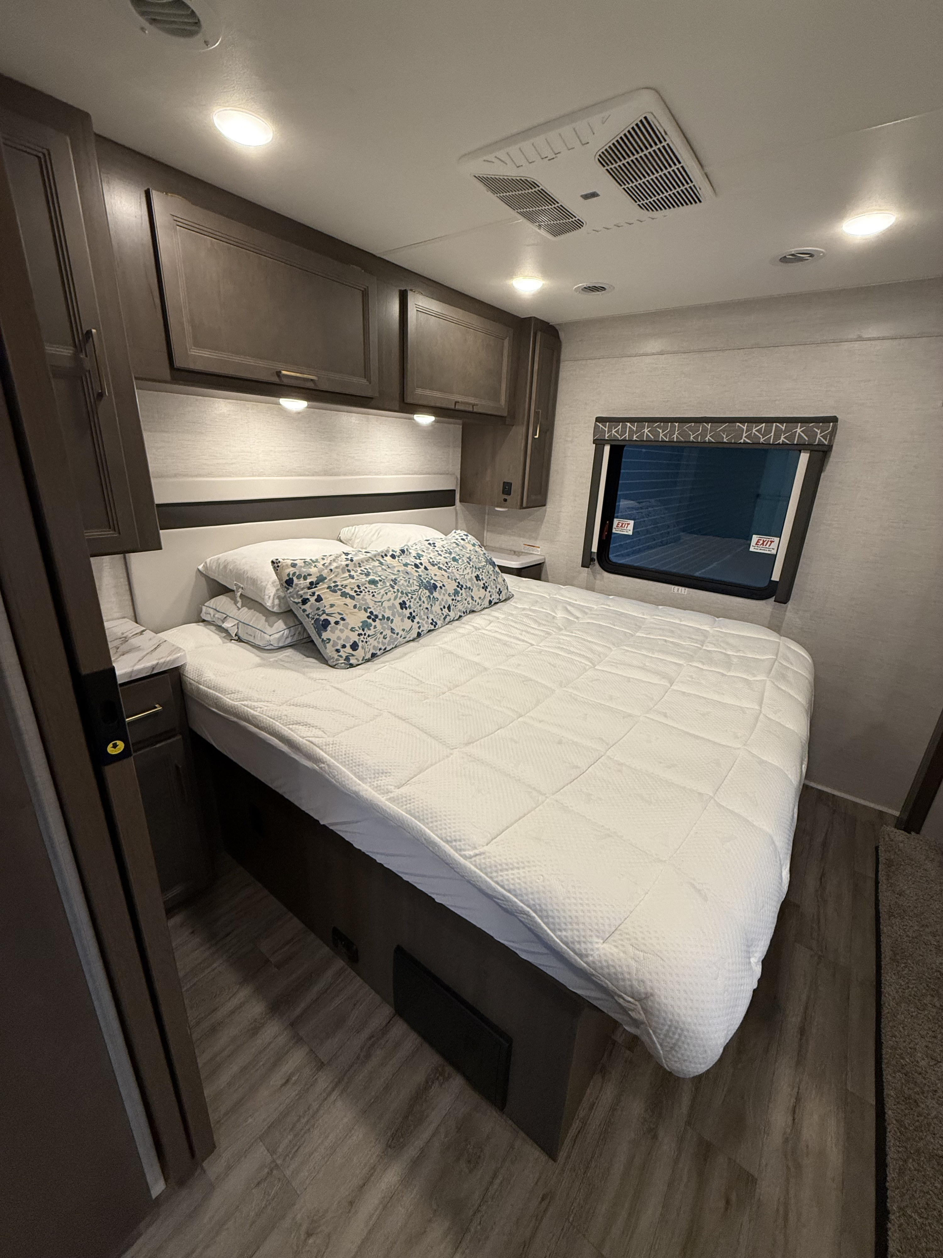 Experience comfort in this RV rental bedroom: queen bed, storage, AC, window, and stylish decor.. Thor Resonate 2024