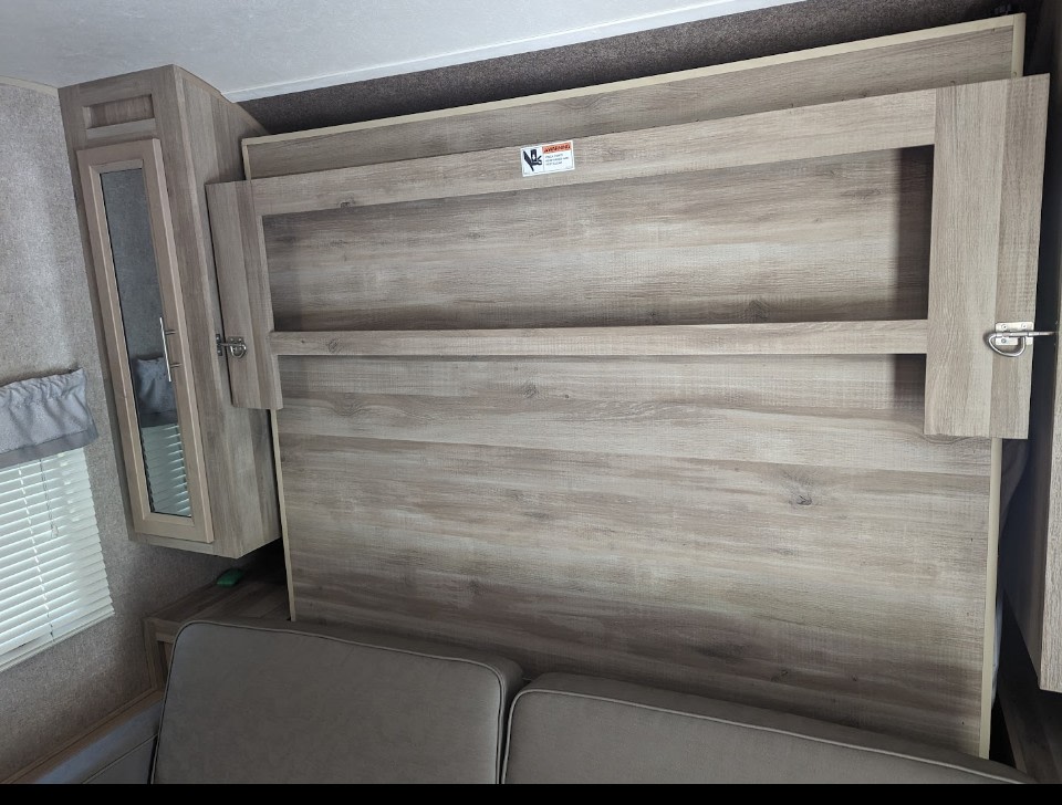 RV rental interior featuring a neatly folded murphy bed over a couch, with a cabinet and window.. Forest River Coachmen Catalina Summit 2020