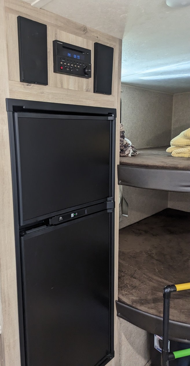 Inside an RV rental: compact refrigerator, entertainment system, and bunk beds, showing efficient use of space for travel.. Forest River Coachmen Catalina Summit 2020