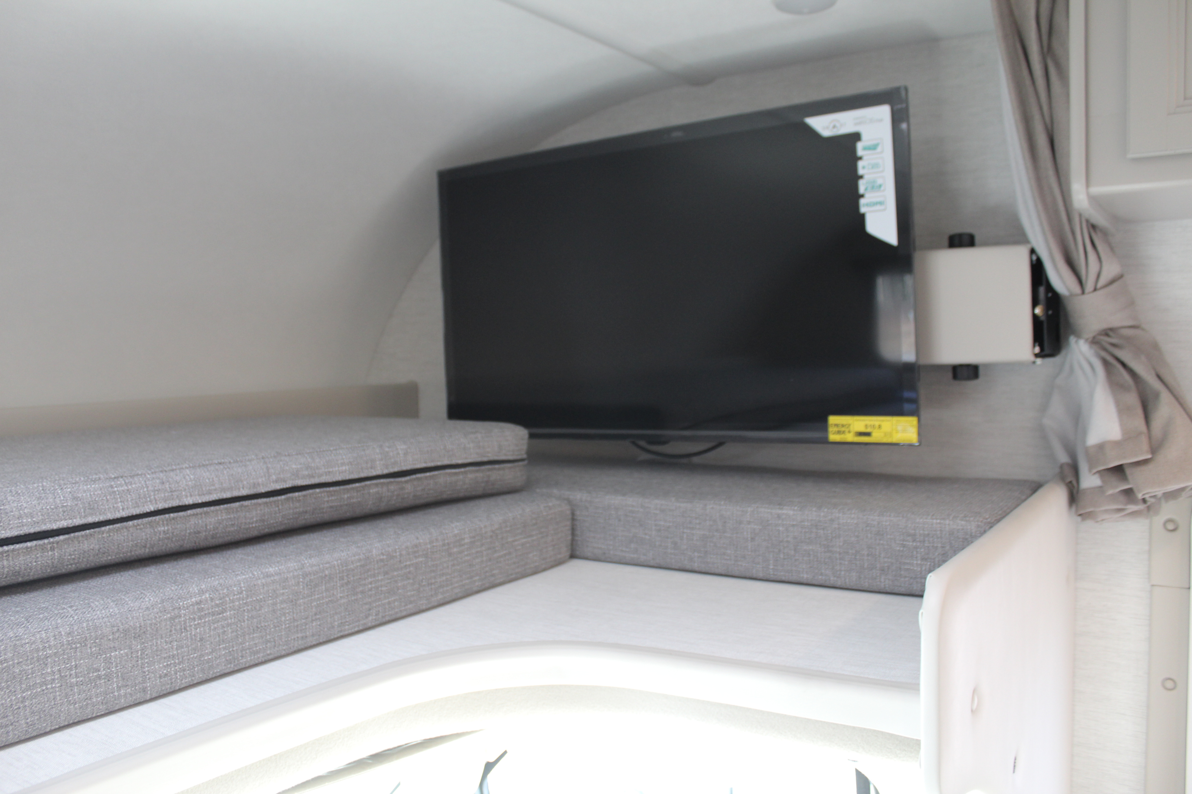 RV rental: sleeping/lounge area with grey cushions and wall-mounted TV for onboard entertainment.. Thor Motor Coach Four Winds 2025