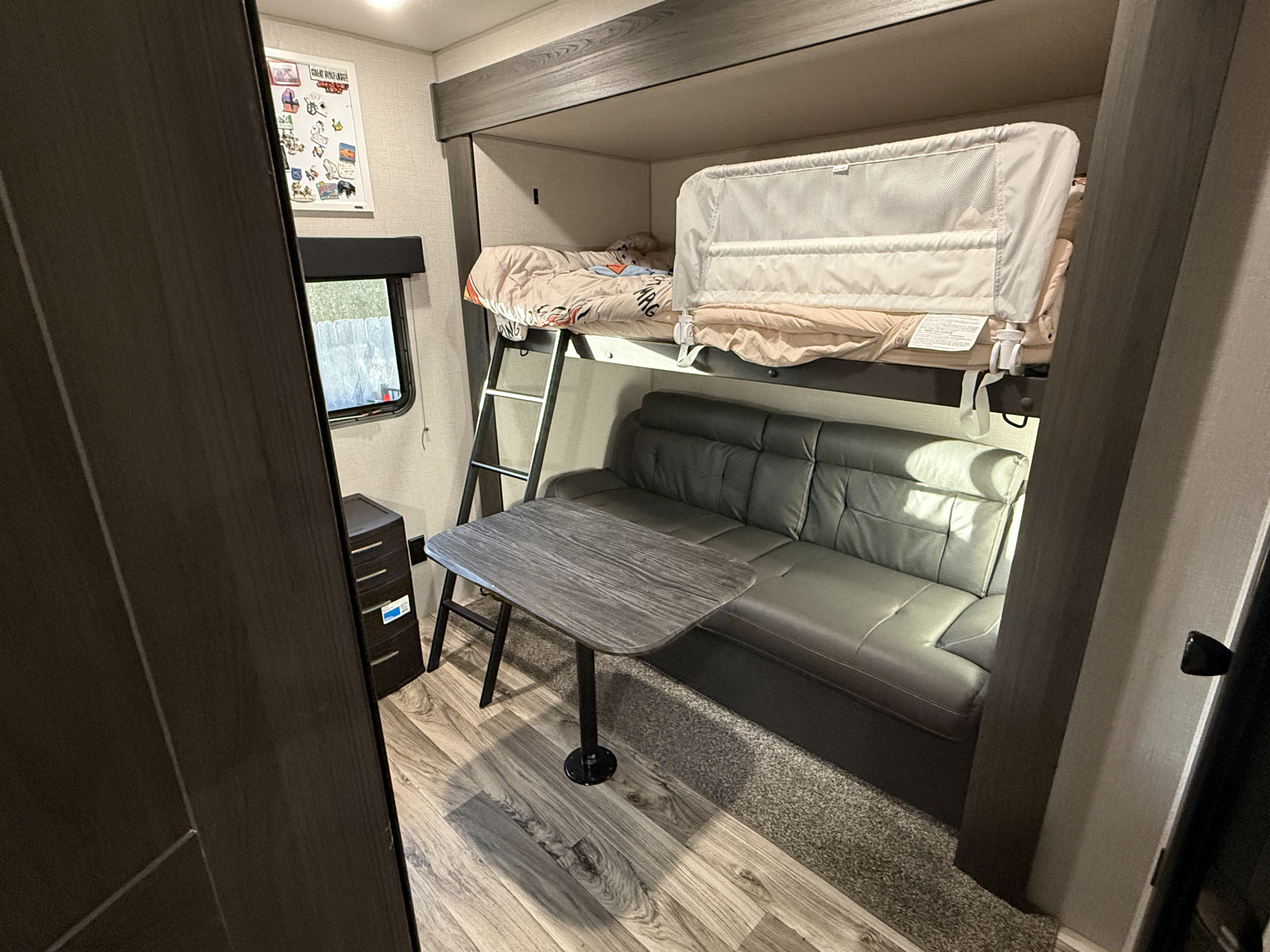 Inside an rv rental: bunk beds with safety rail, convertible sofa, dining table, and window view for comfortable travel.. Sport Trek Sport Trek Trailer 2021