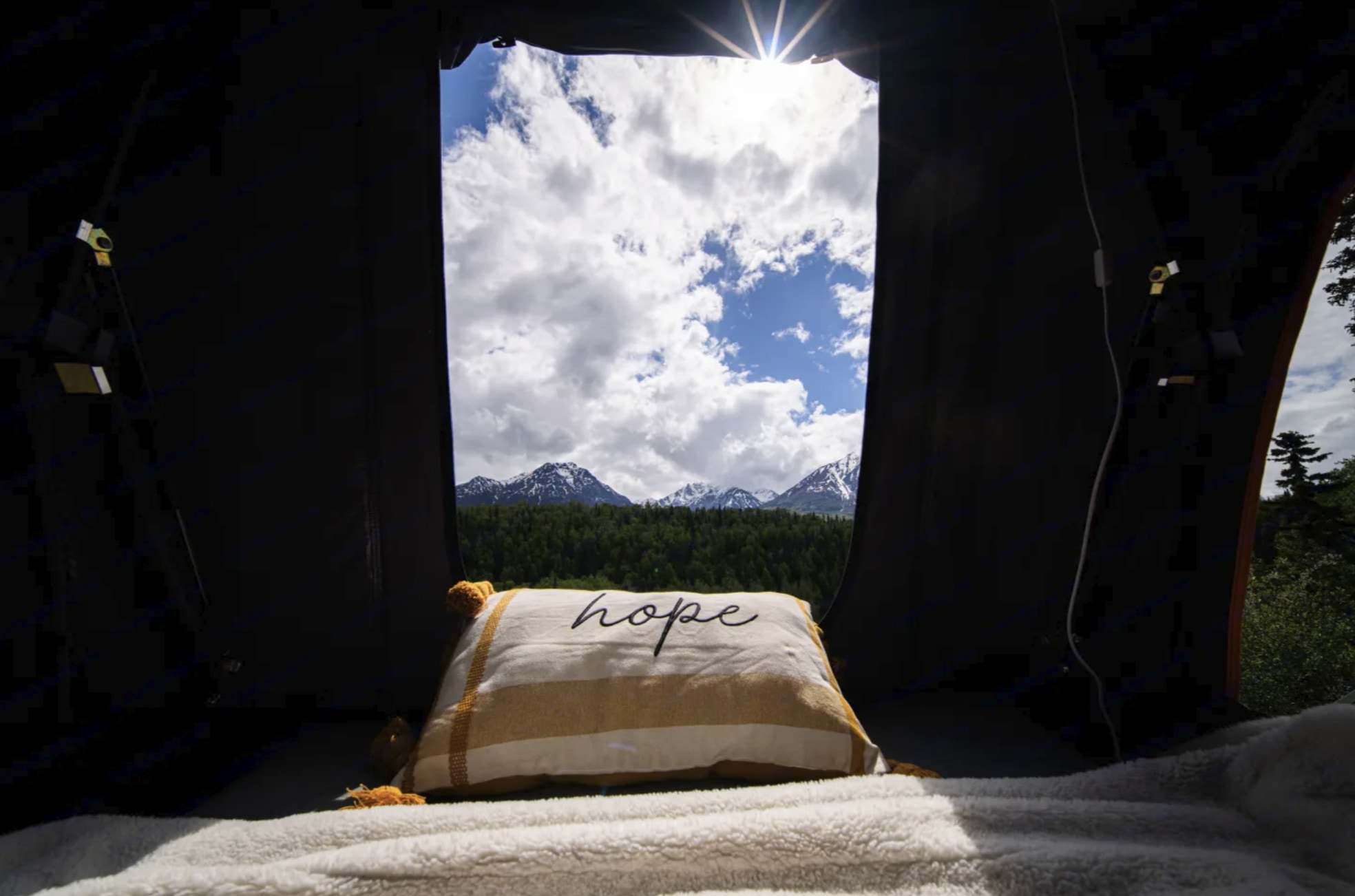 Cozy RV rental view of snow-capped mountains & forest, with a 'hope' pillow. Experience serene nature, a perfect outdoor escape.. Toyota Highlander Roof Tent Camper 2015