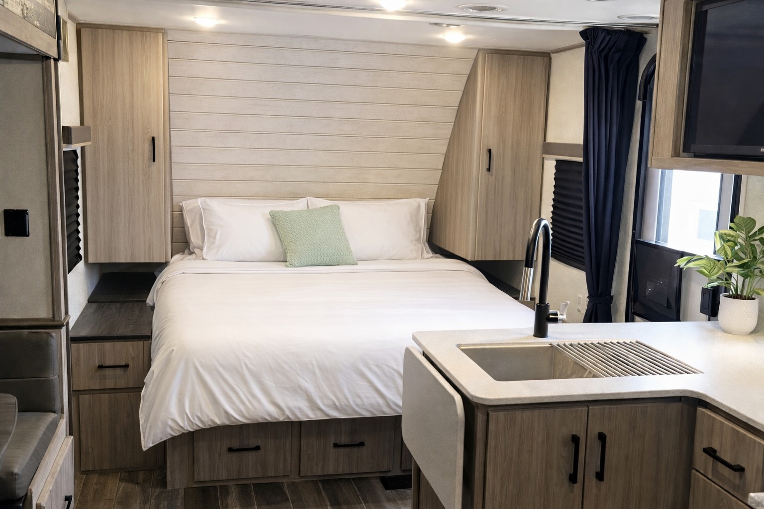 Modern RV rental interior featuring a cozy bed with a green pillow, sleek light wood cabinetry, and a compact kitchen sink.. Keystone Passport Sl series 2021