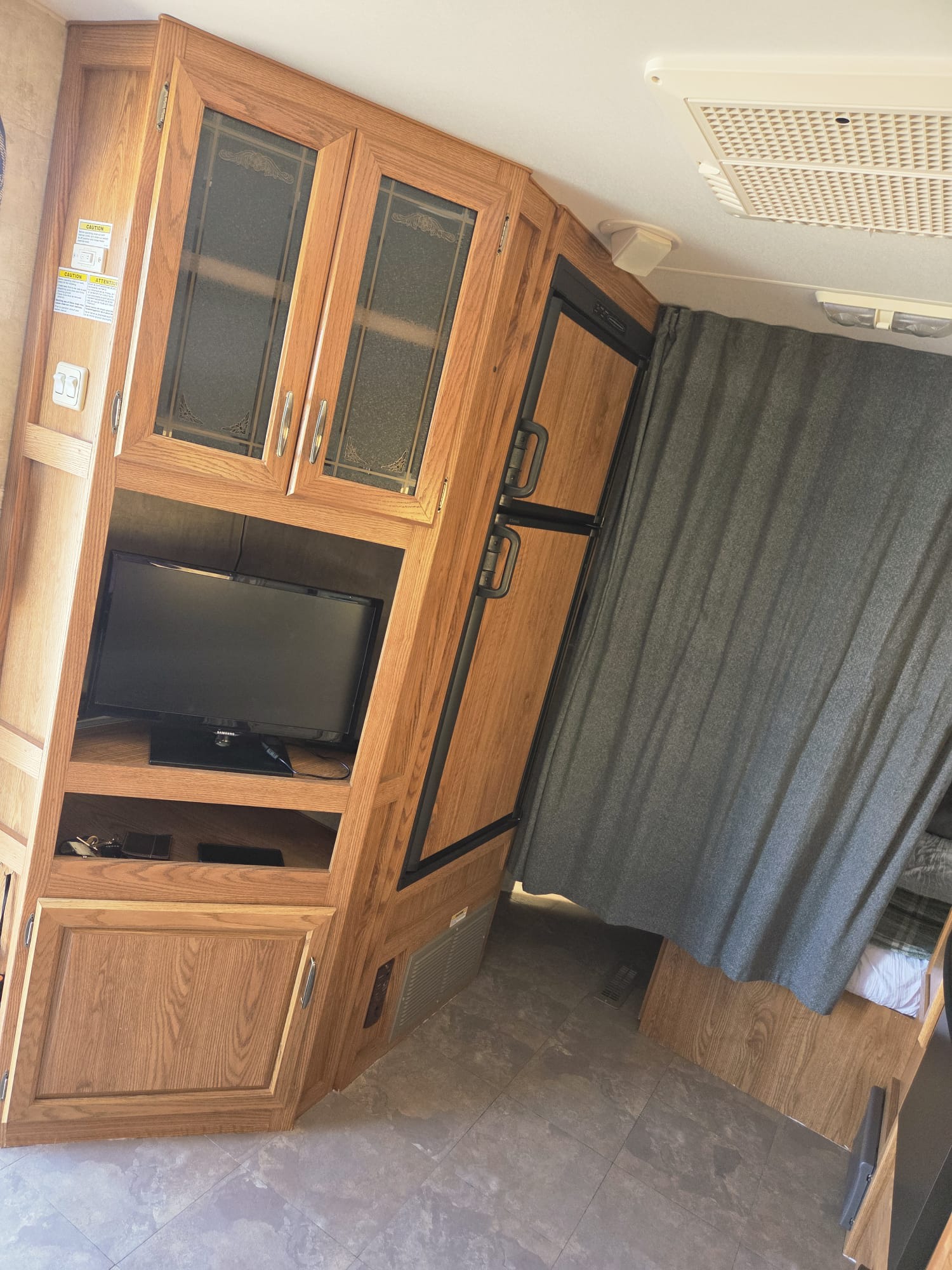 RV rental: interior with light wood cabinetry, TV, compact fridge, and sleeping nook behind a curtain.. Prowler Prowler Fifth Wheel 2006