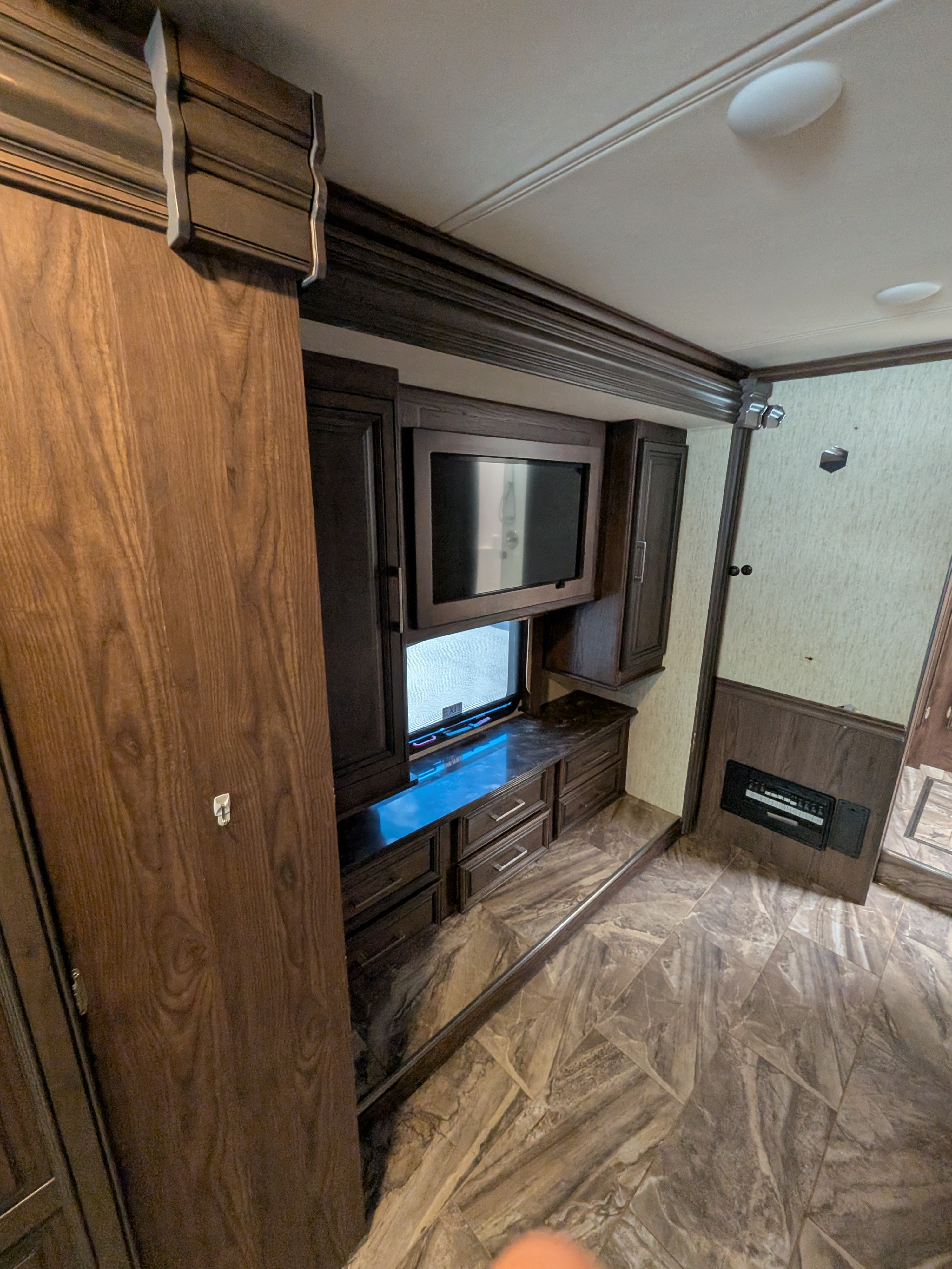 Modern RV rental interior featuring a compact entertainment center, dark wood cabinetry, and stylish tiled flooring.. Forest River Coachmen Sportscoach SRS 2020