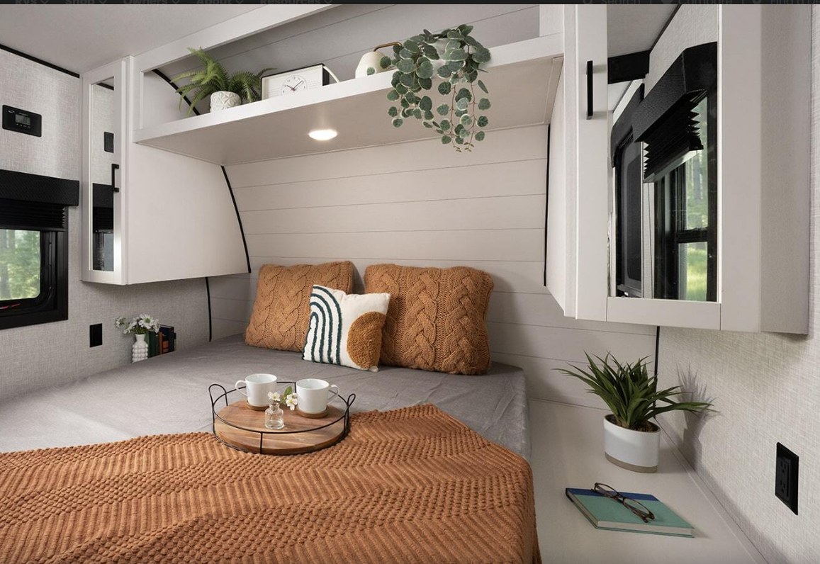 Cozy RV rental bedroom interior with a comfy bed, modern decor, plants on shelves, and bright windows for a relaxing stay.. Highland Ridge RV Open Range 2025